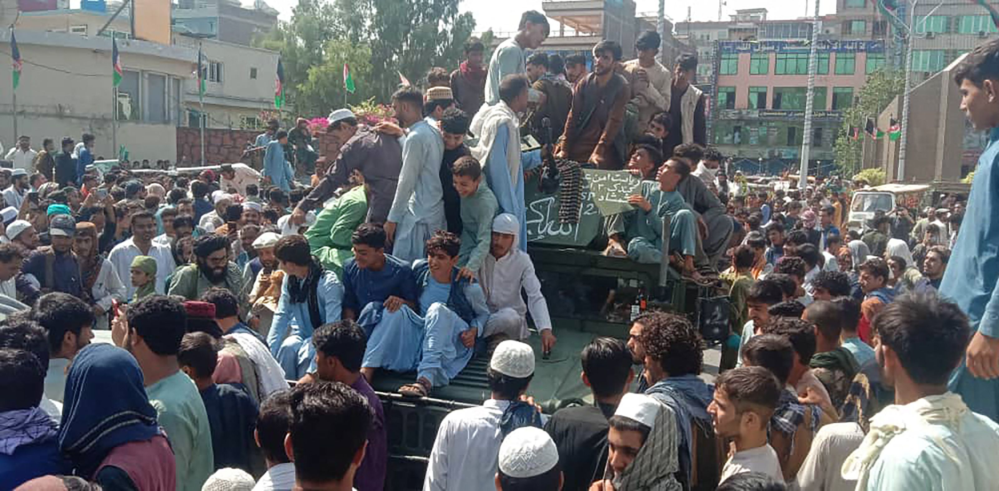 Taliban fighters and local people sit on an Afghan National Army (ANA) Humvee vehicle on a street in Jalalabad province on August 15