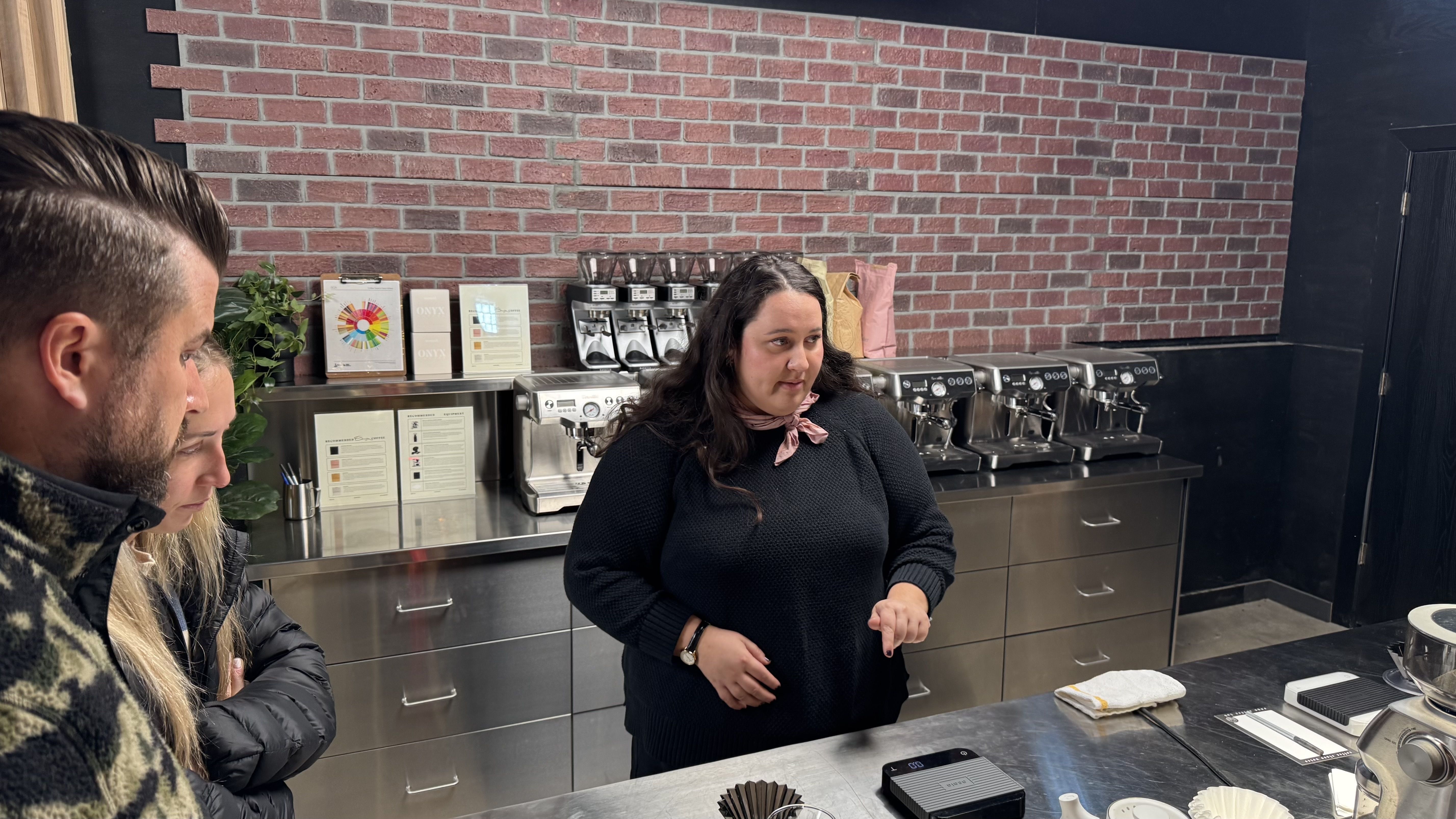 Derek Childers and Gabby Jaques listen to instructions from Vanessa DeGraffenried at Onyx Coffee Academy.