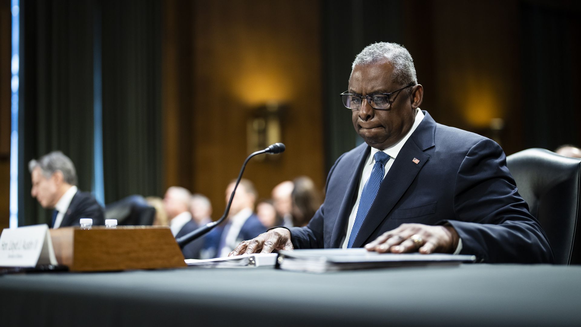 Defense Secretary Lloyd Austin, wearing a blue suit, white shirt and blue tie, testifies to a Senate committee.
