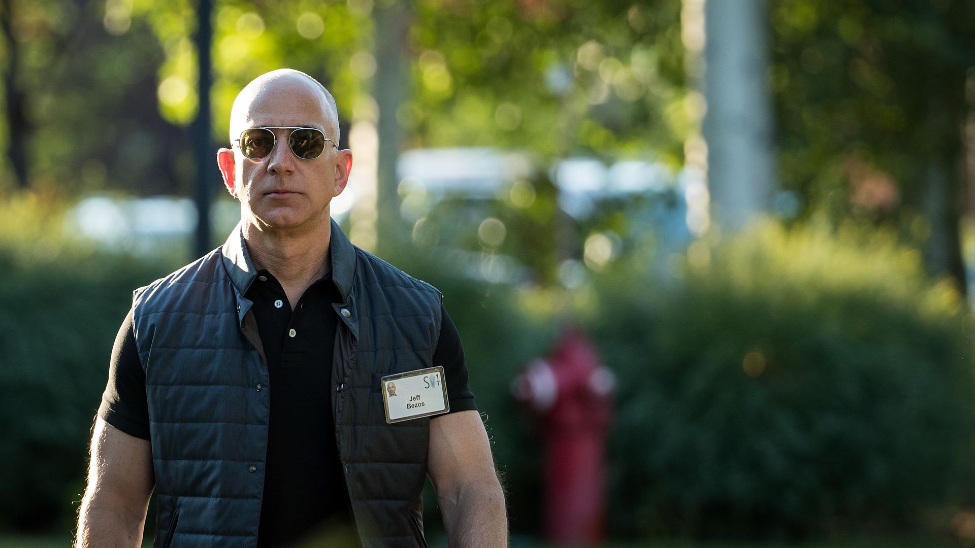 Amazon founder Jeff Bezos walks outside in a short-sleeved polo shirt and vest
