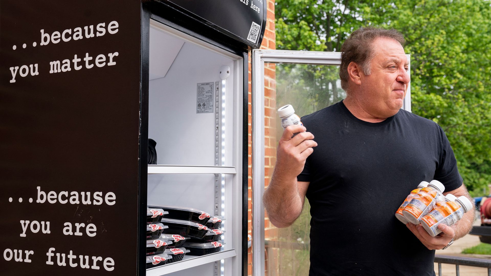 Photo shows Mark Bucher putting baby food in a Feed the Fridge community fridge.