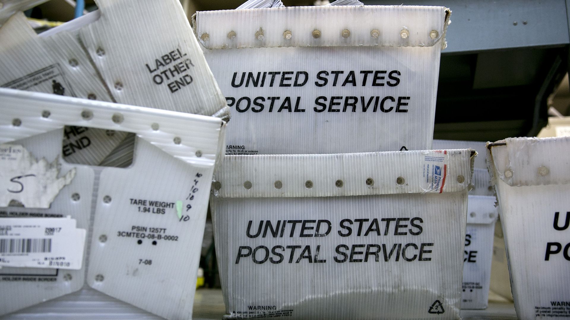 A pile of mail-transport bins reading "United States Postal Service."