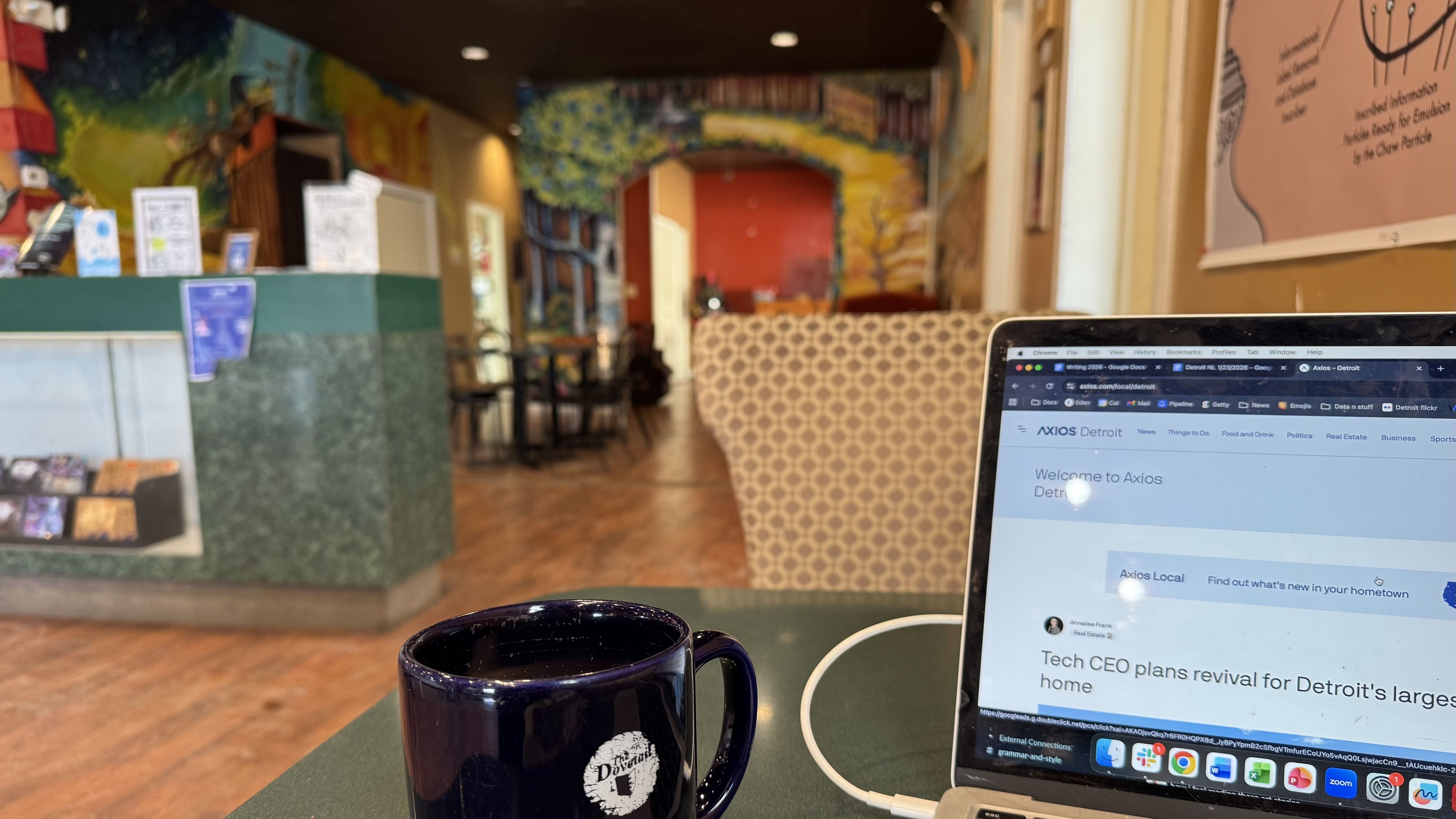 A laptop and coffee mug, with murals in the background