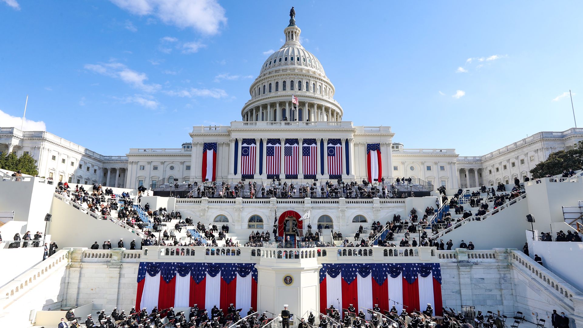 A wide shot of the Capitol building with flags draped down the side as President Biden gives his inaugural address
