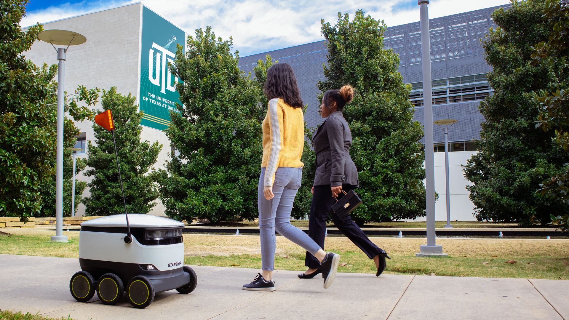 A sidewalk robot strolls down the sidewalk at the University of Texas in Dallas.