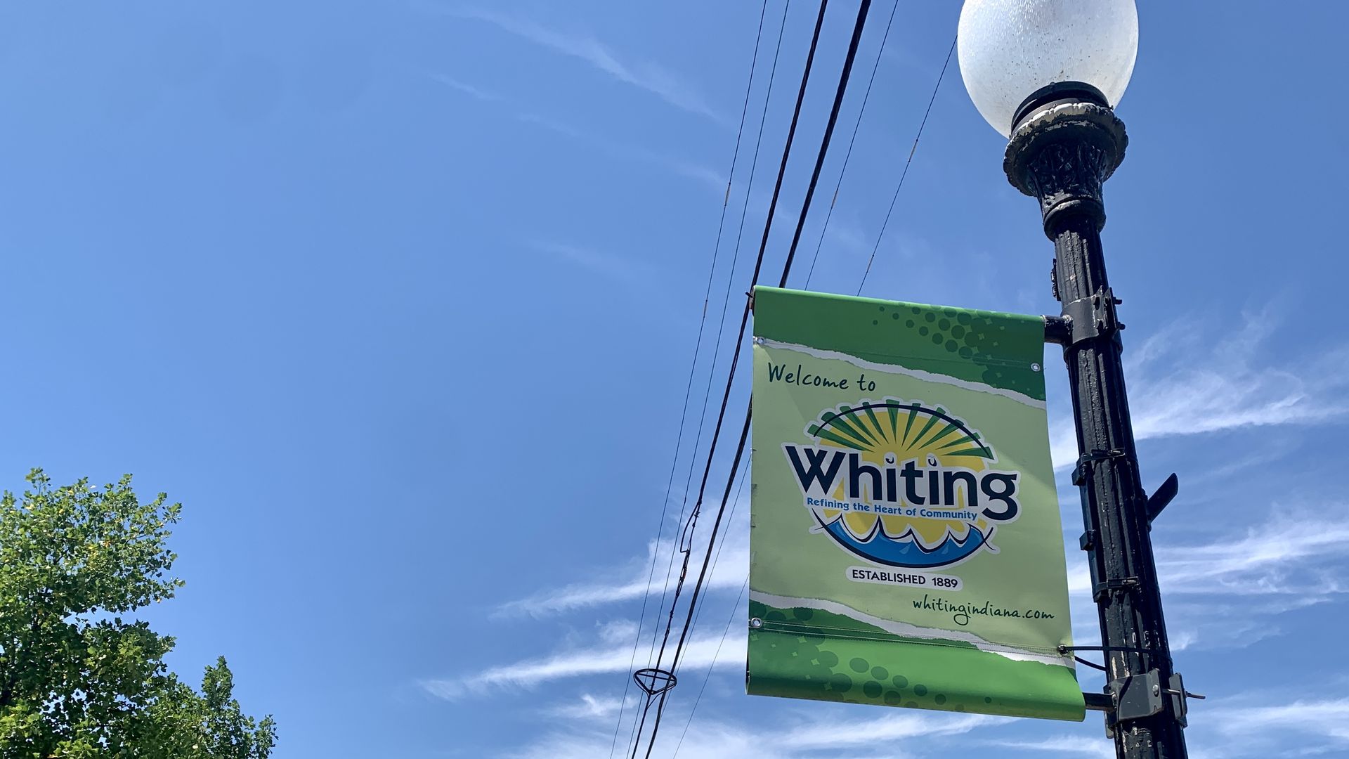 Black lightpost with green banner that reads "Welcome to Whiting" 
