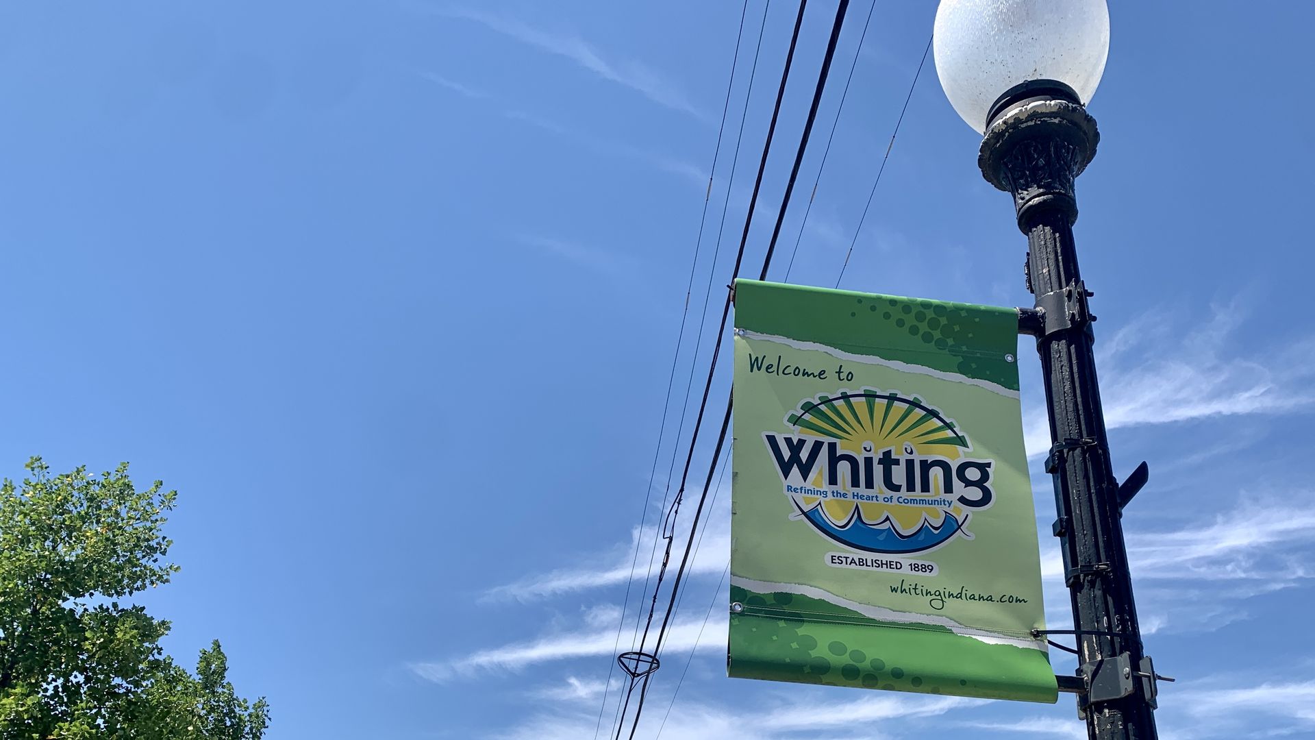 Black lightpost with green banner that reads "Welcome to Whiting"