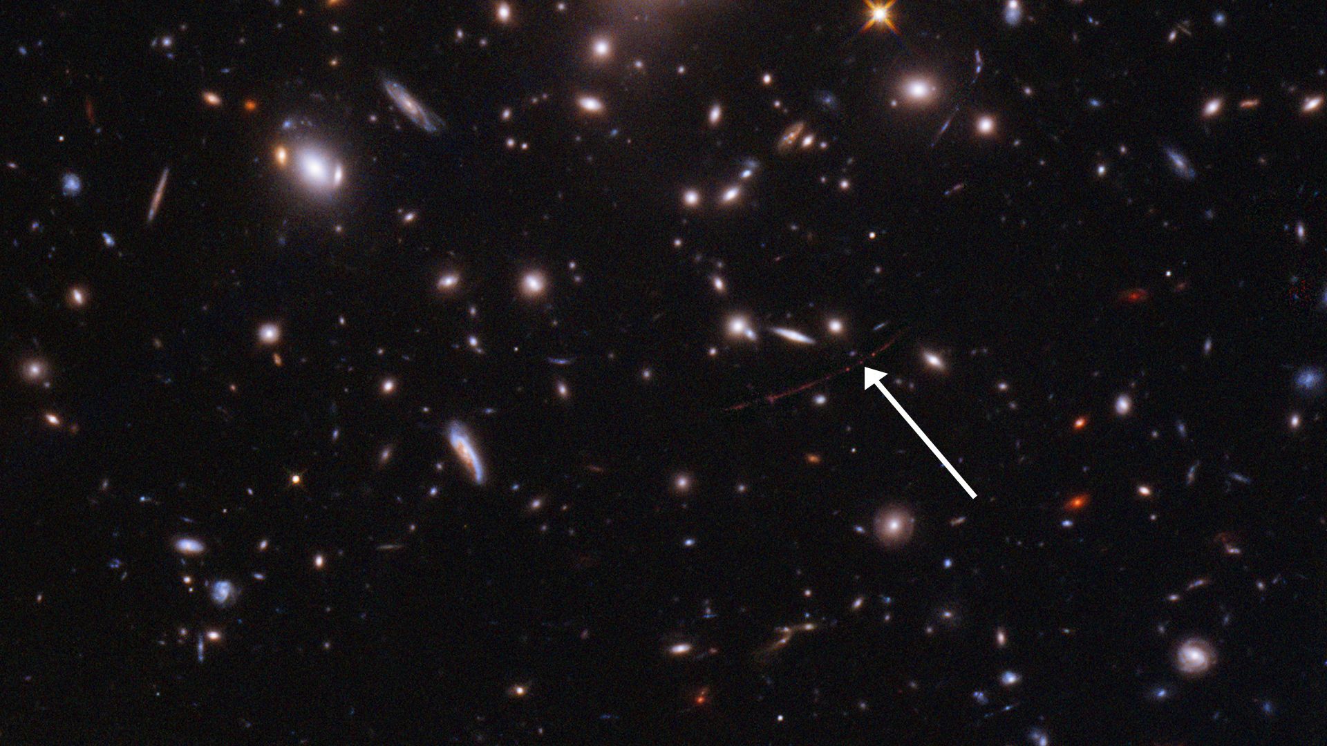 Deep space image of galaxies and arrow pointing to newly detected star 