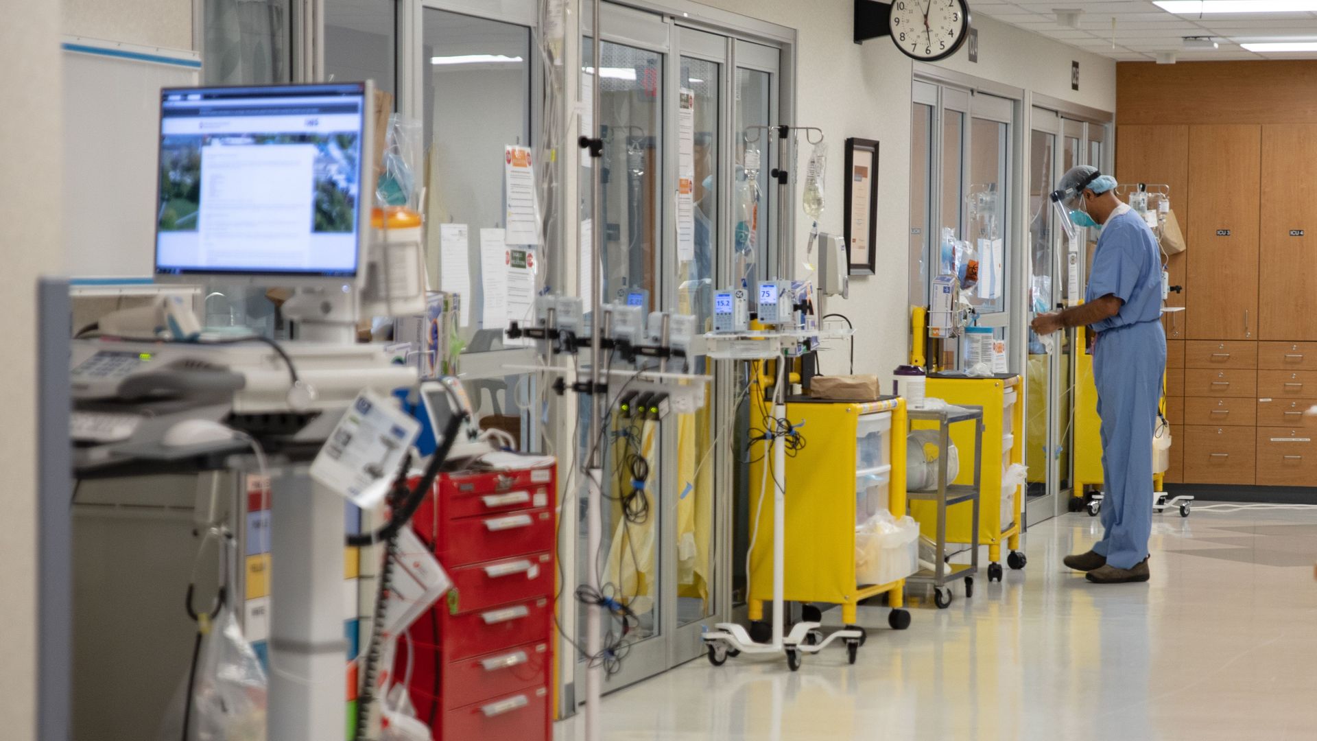 Photo of a health care worker standing outside an ICU room in a hospital ward