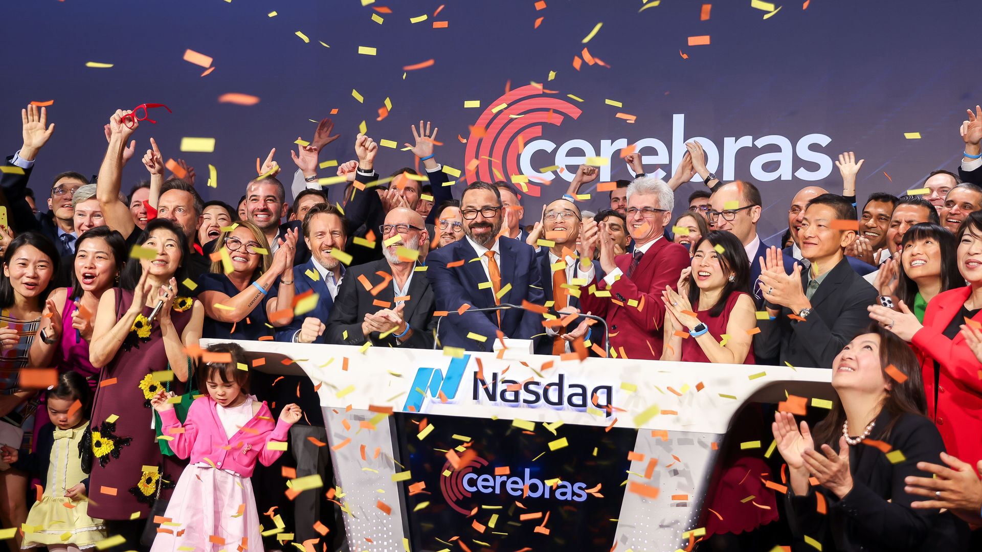 Large diverse crowd on a stage celebrating with orange and yellow confetti falling; many raise hands. In the background, the Cerebras logo and a Nasdaq banner.