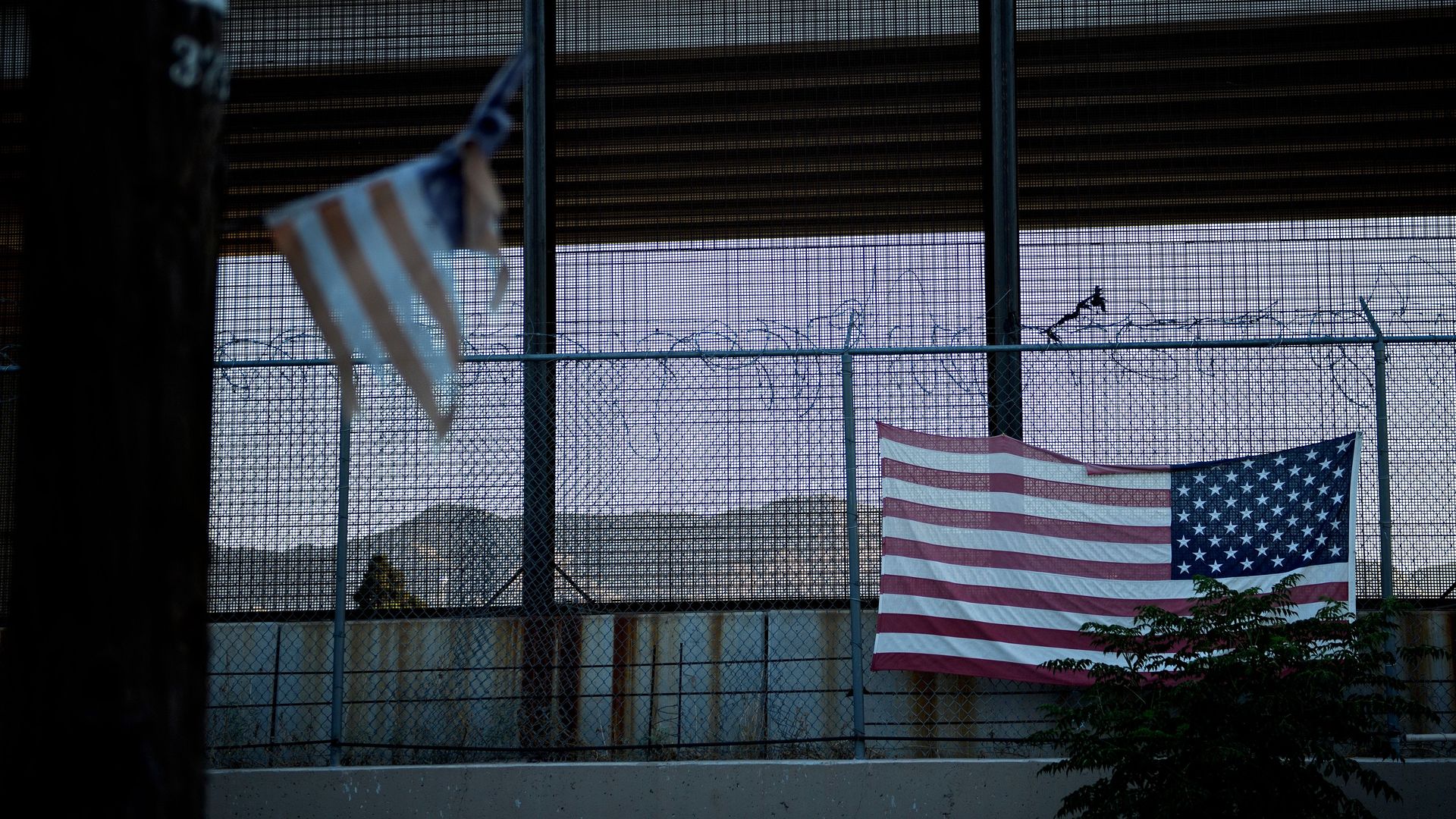 A U.S. flag hanging on a chain-link fence.