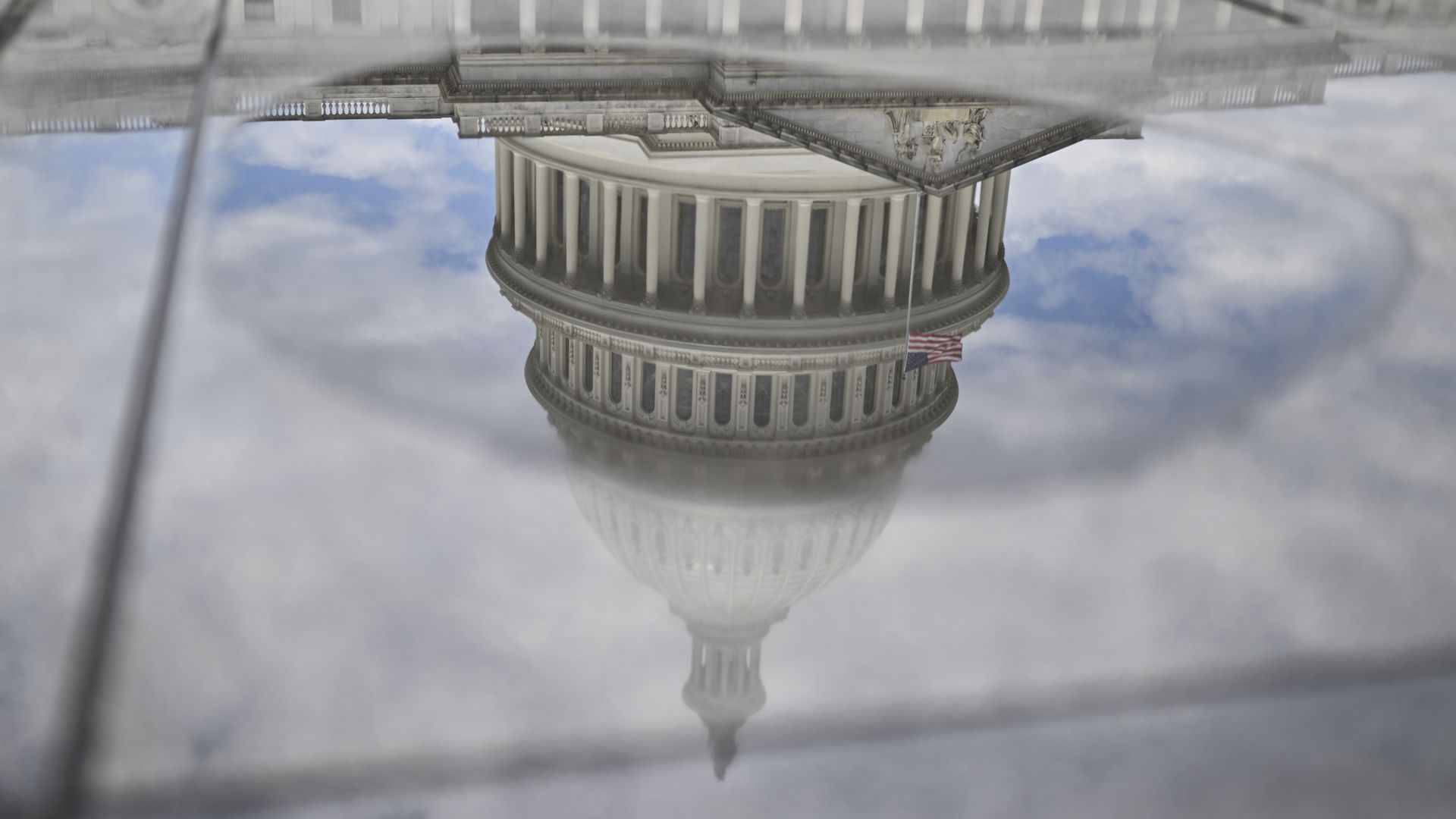 The U.S. Capitol dome pictured upside down in a reflection off a puddle of rainwater
