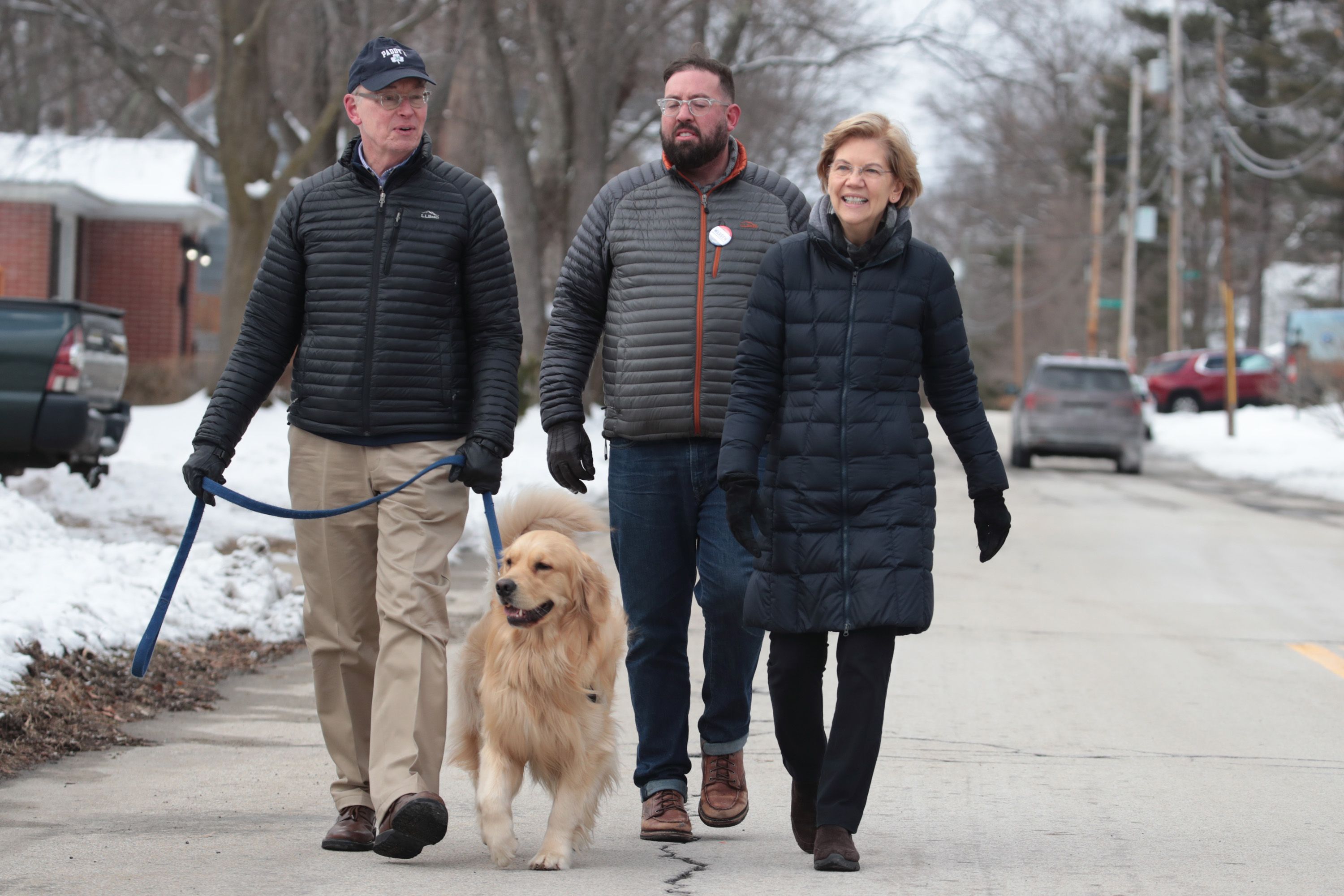 Democratic presidential candidate Sen. Elizabeth Warren (D-MA) canvases a neighborhood with her husband Bruce (L), her dog Bailey and campaign volunteer Colin Pio on February 08