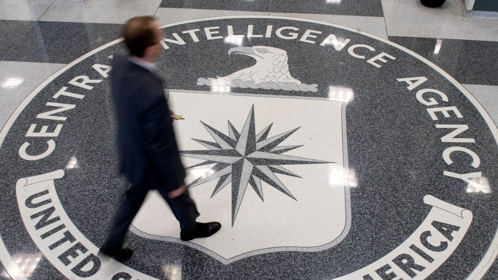 A man crosses the CIA seal in the agency's headquarters