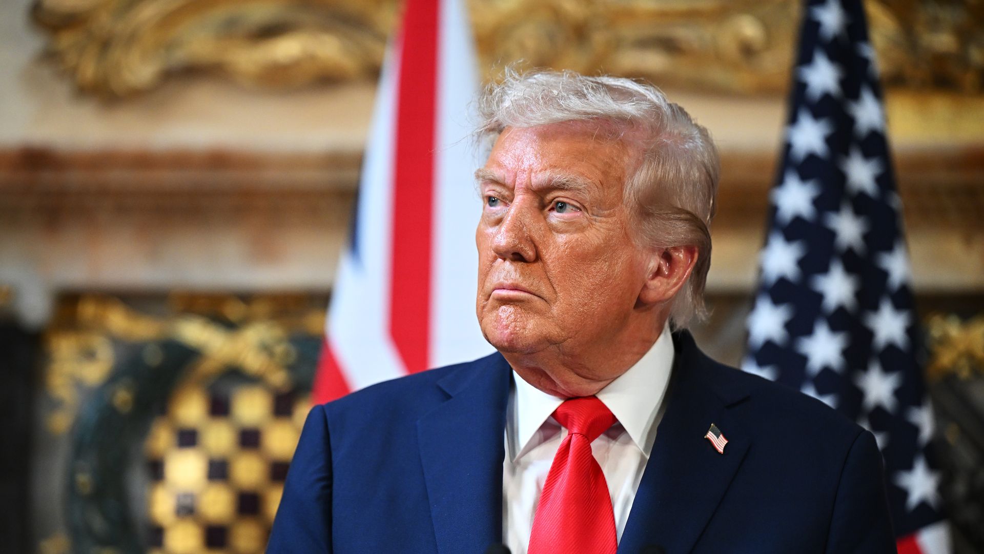 Man in blue suit and red tie looks off to the side