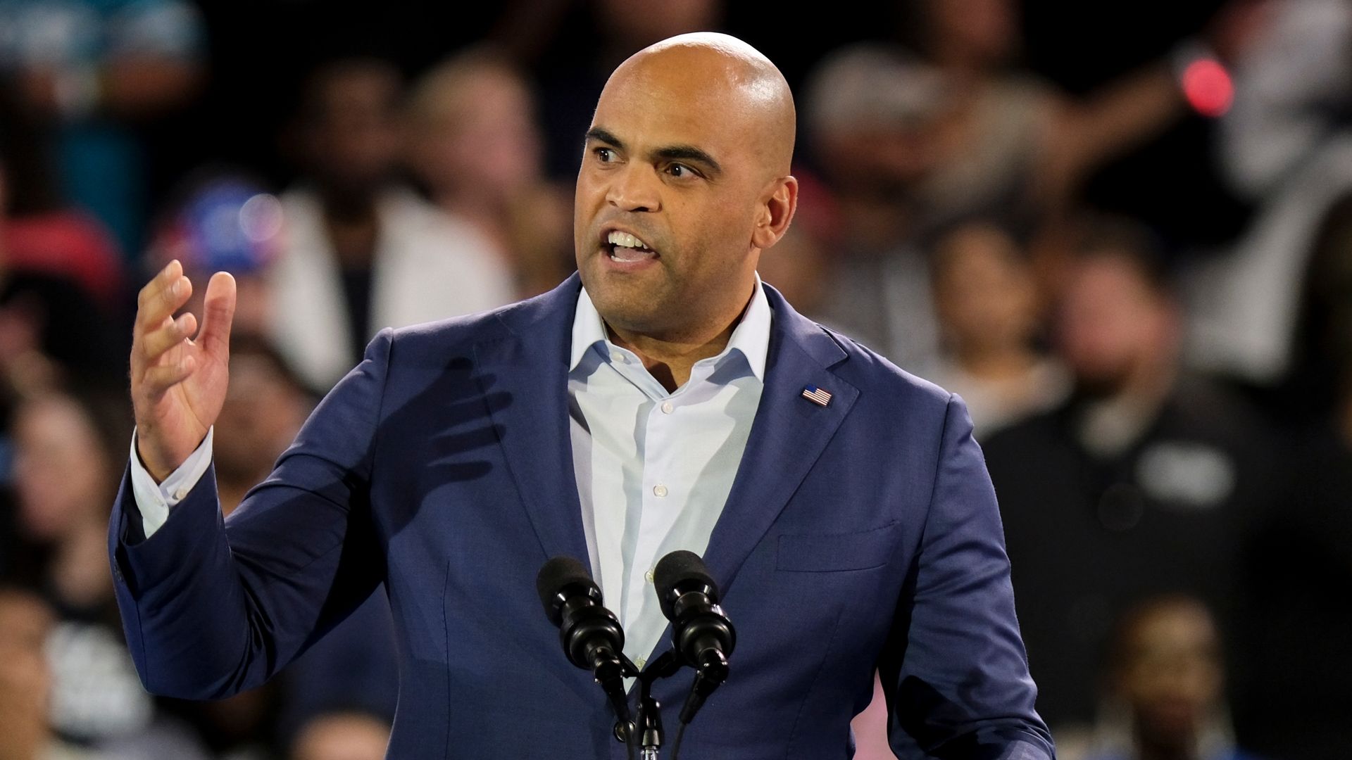 Colin Allred standing at a podium at an outdoor stadium rally.