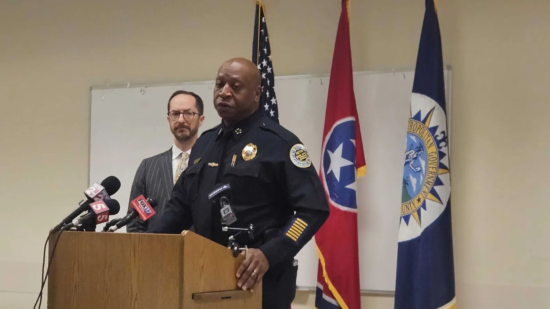 Police chief standing at podium with mayor standing behind him
