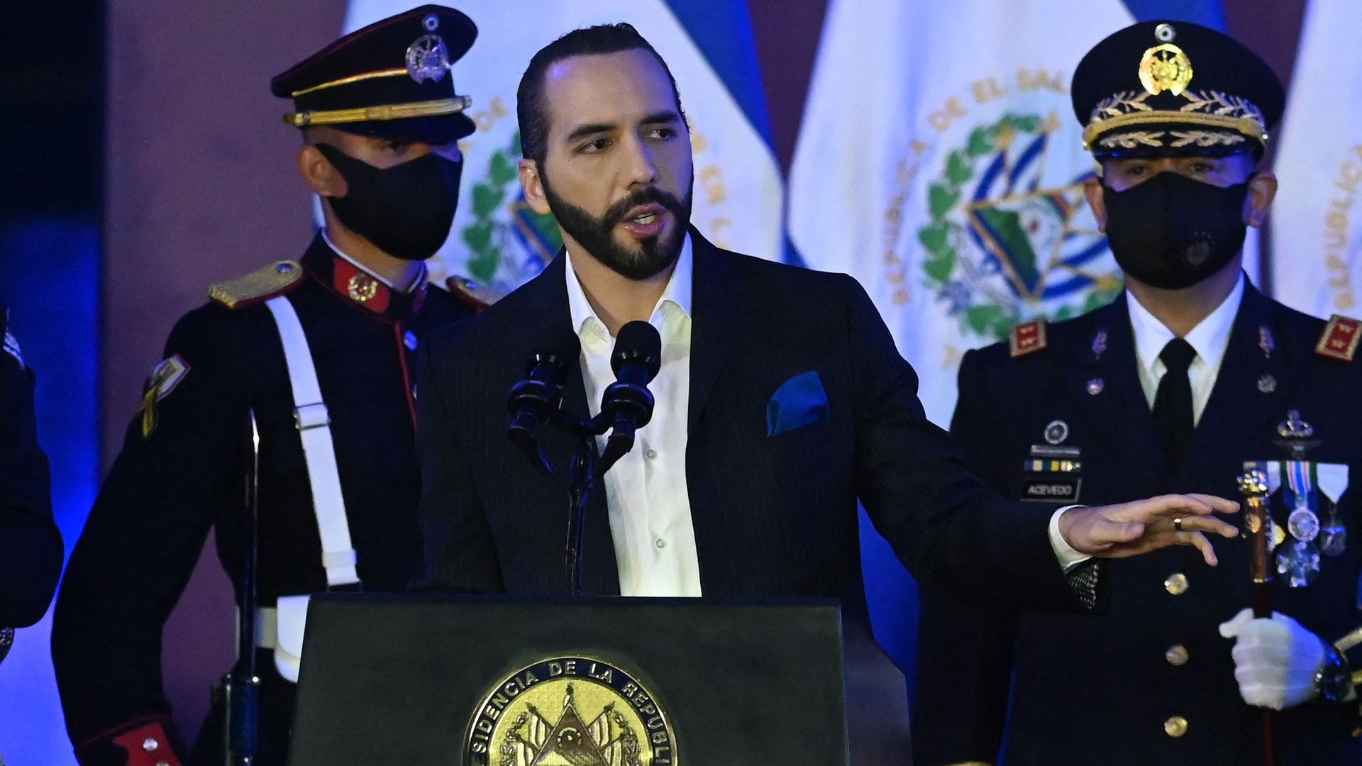 El Salvador President Nayib Bukele stands behind a podium with the presidential seal. 