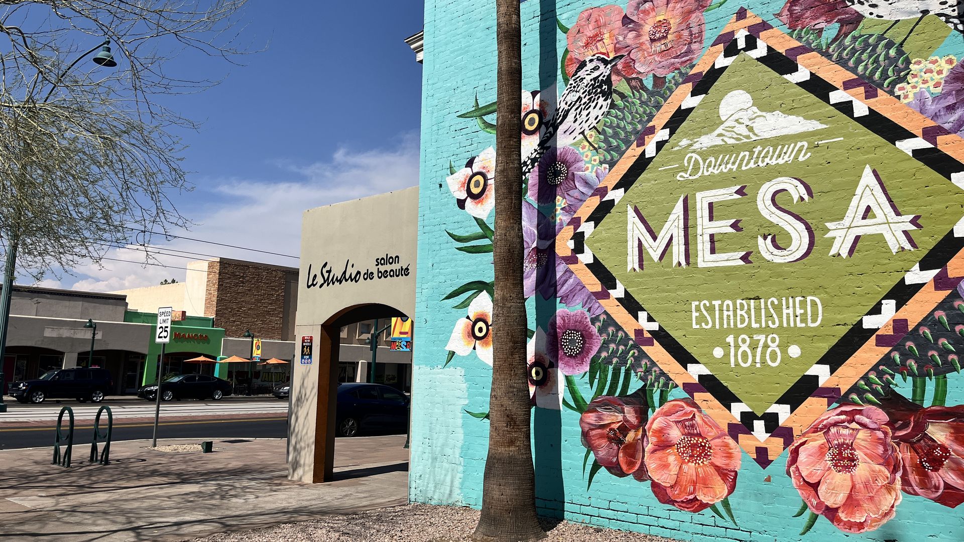 A sign that says downtown Mesa with shops in the background. 