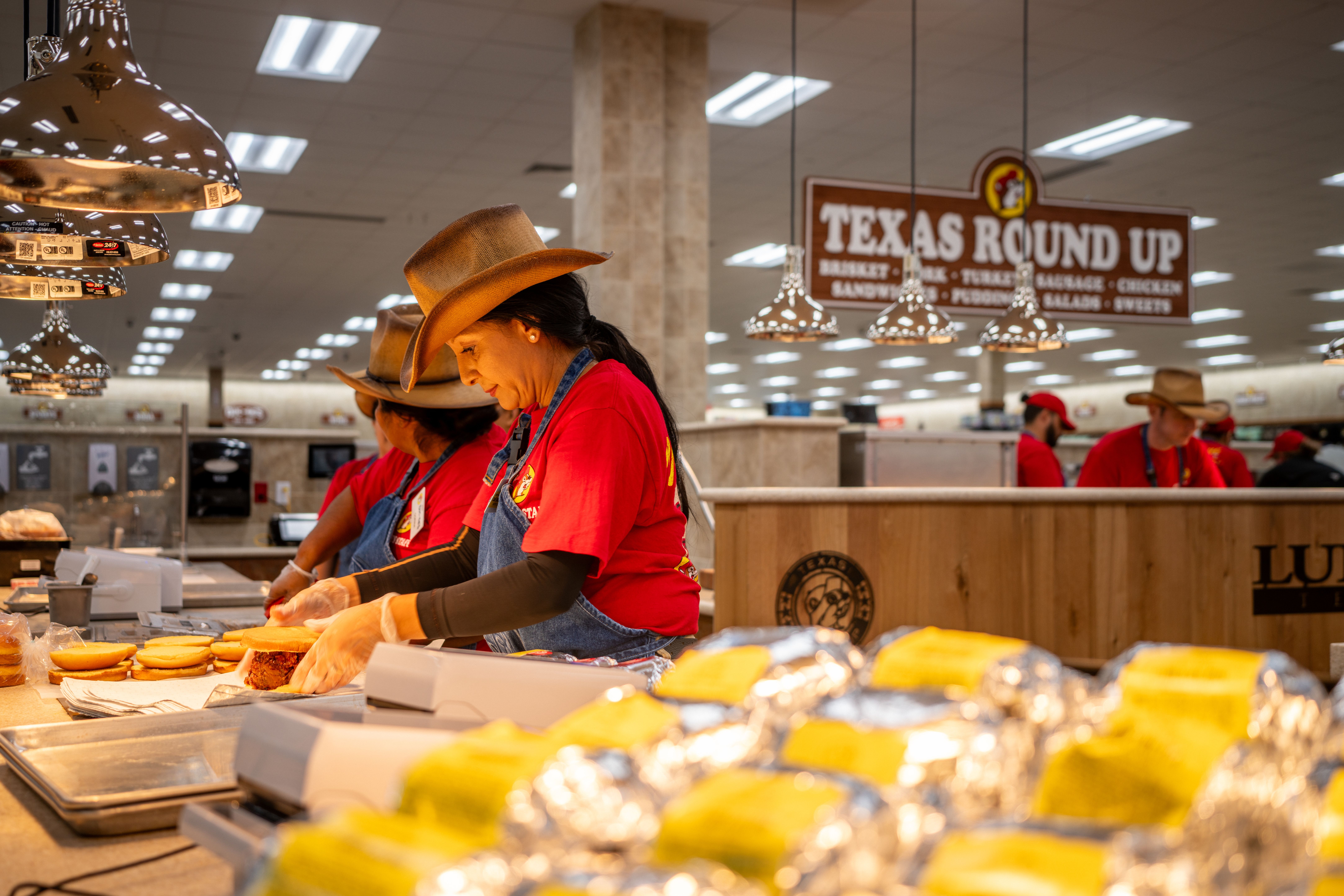 Image shows a woman making bbq sandwiches.