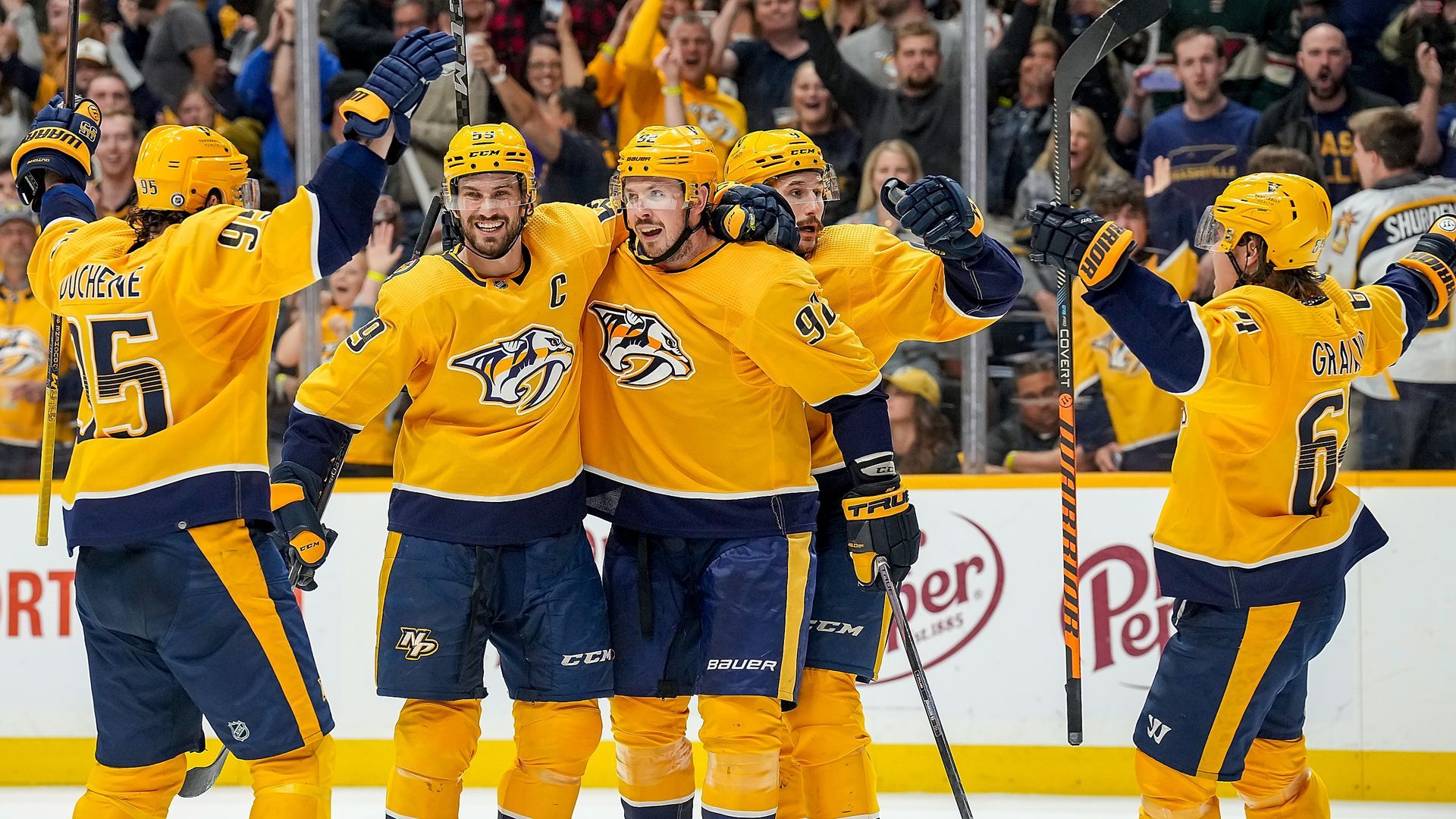 Nashville predators players in gold/yellow uniforms celebrating a goal