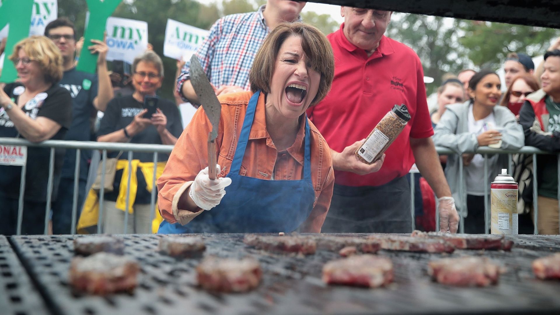 Women stands over grill cooking hamburgers at Steak Fry