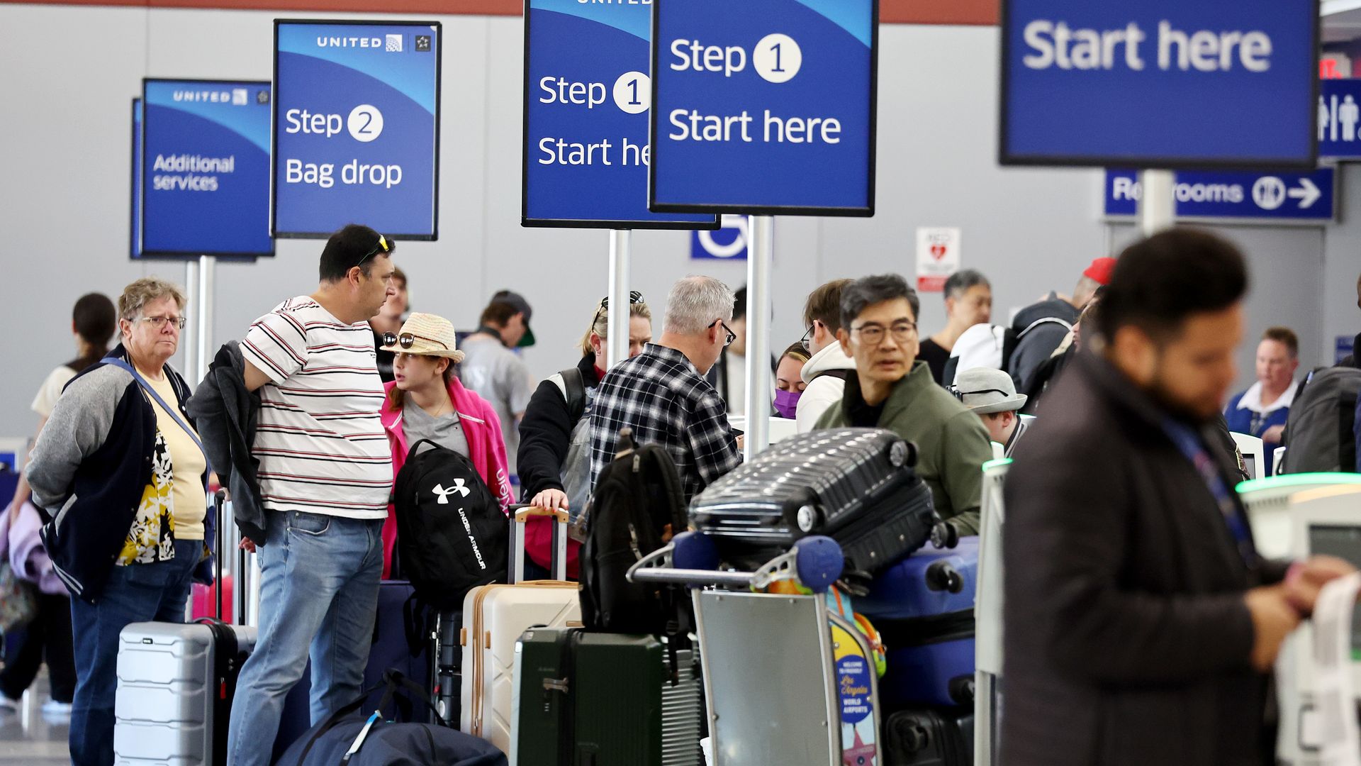 Travelers stand at a United Airlines check-in area at Los Angeles International Airport (LAX) 