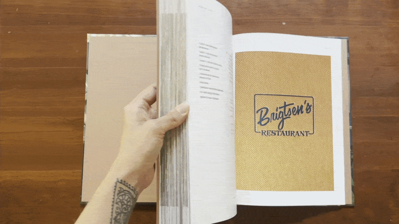 A person flips through the pages of a cookbook called "Color of Flavor."