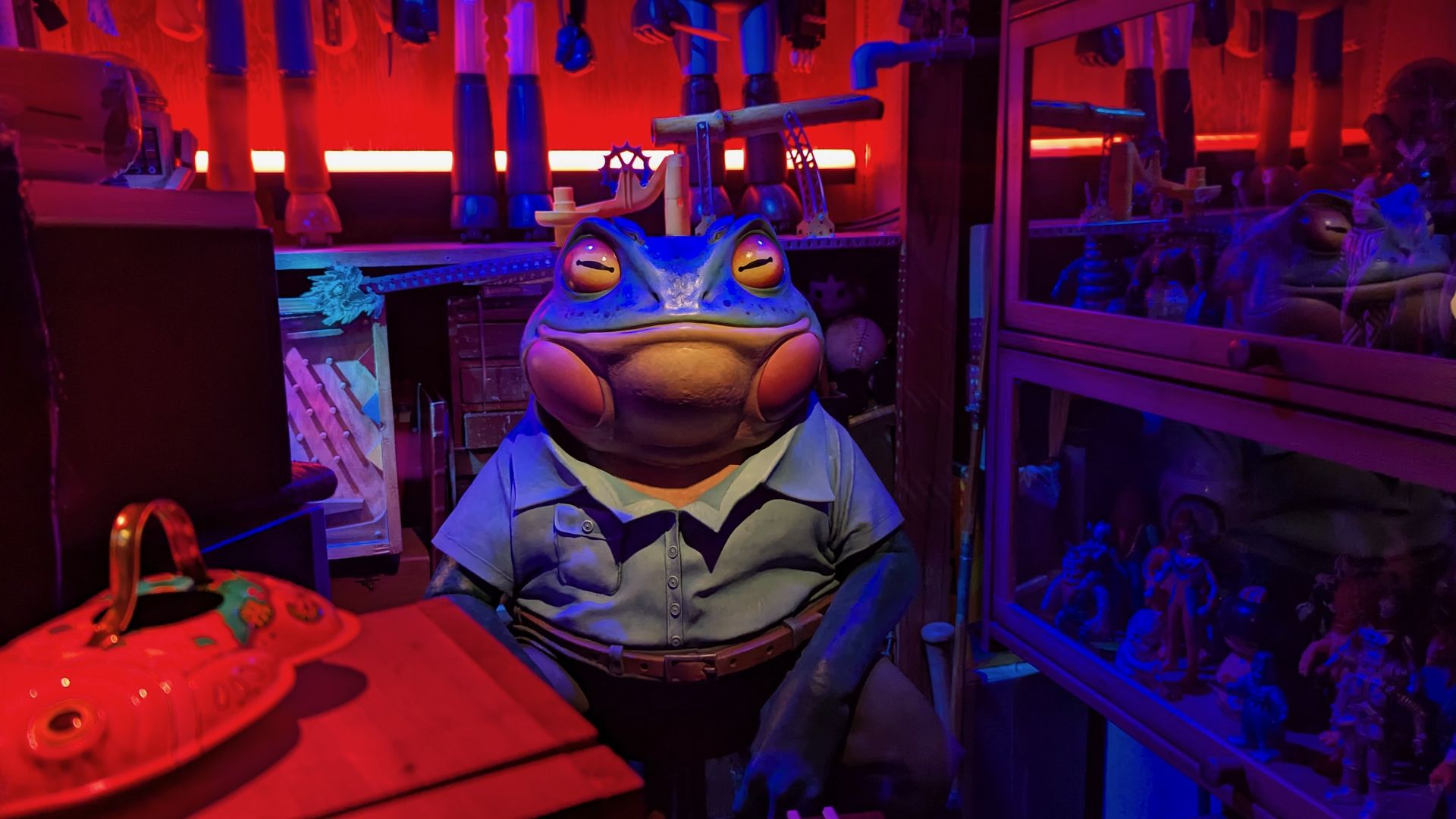 A large frog figure sits in a display of vintage electronics