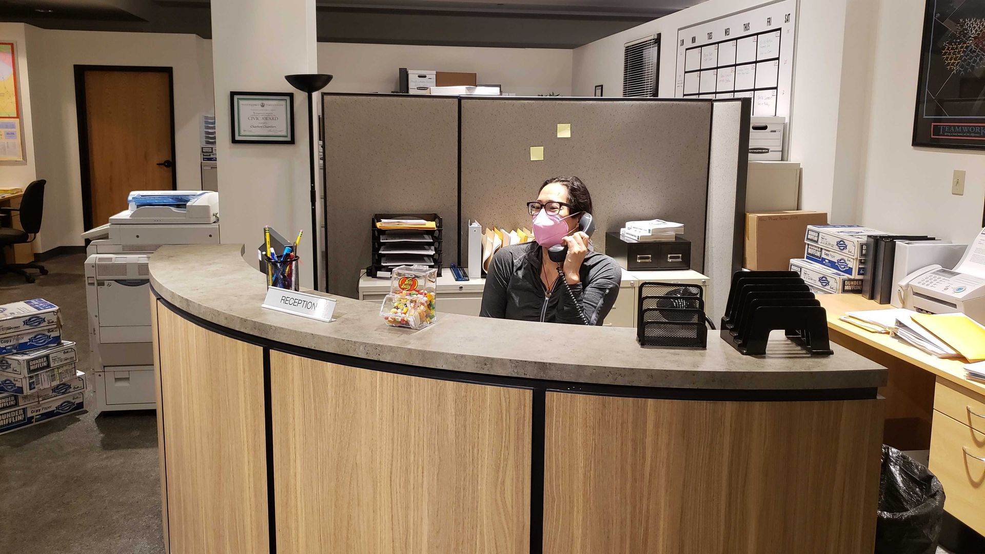 Monica answers phone behind a desk.