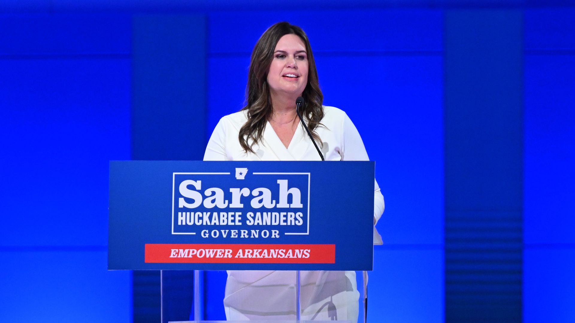 A photo of Arkansas Gov. Sarah Huckabee Sanders standing at a podium.