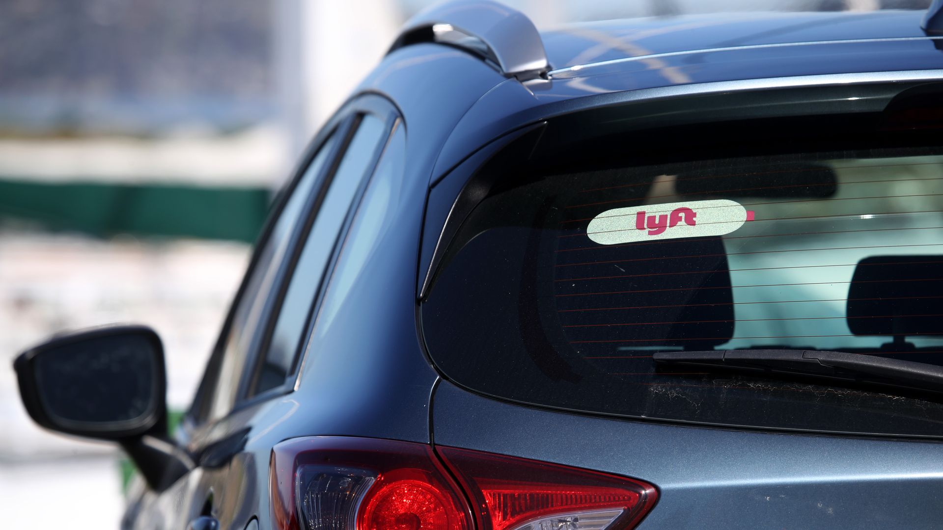 The back of a car shows a Lyft driver sticker in the window.