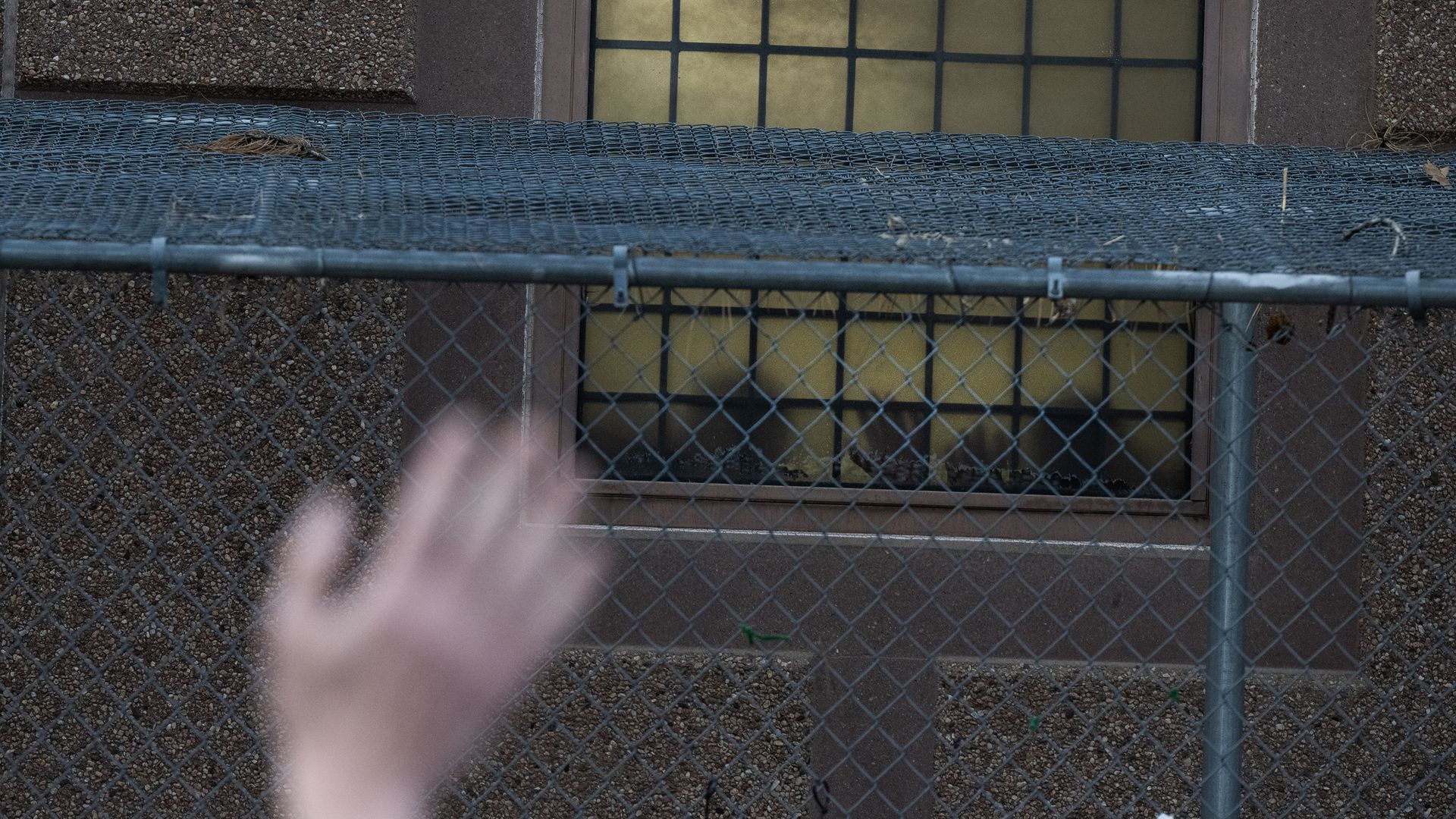 Detainees place their hands against a window outside the Aurora ICE Processing Center during a Passover Grief Vigil.