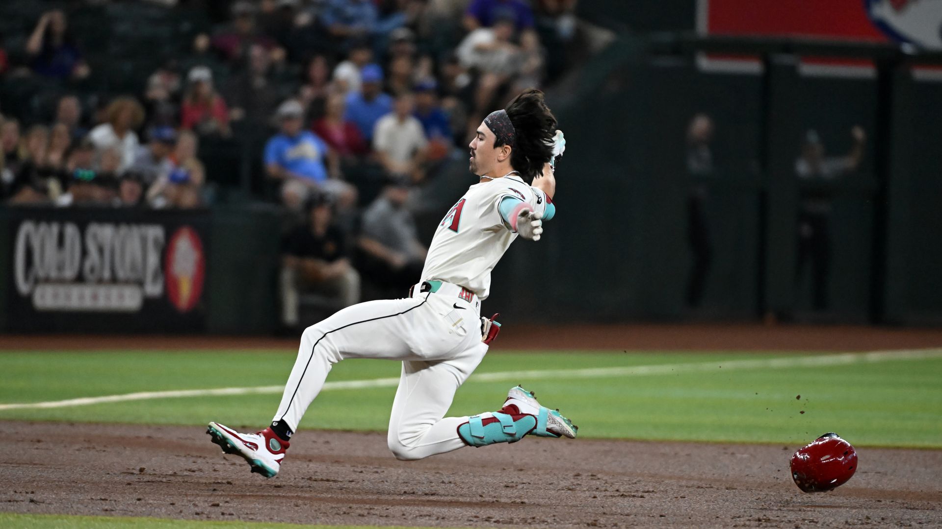 Corbin Carroll slides into third base with his arms outstretched. 