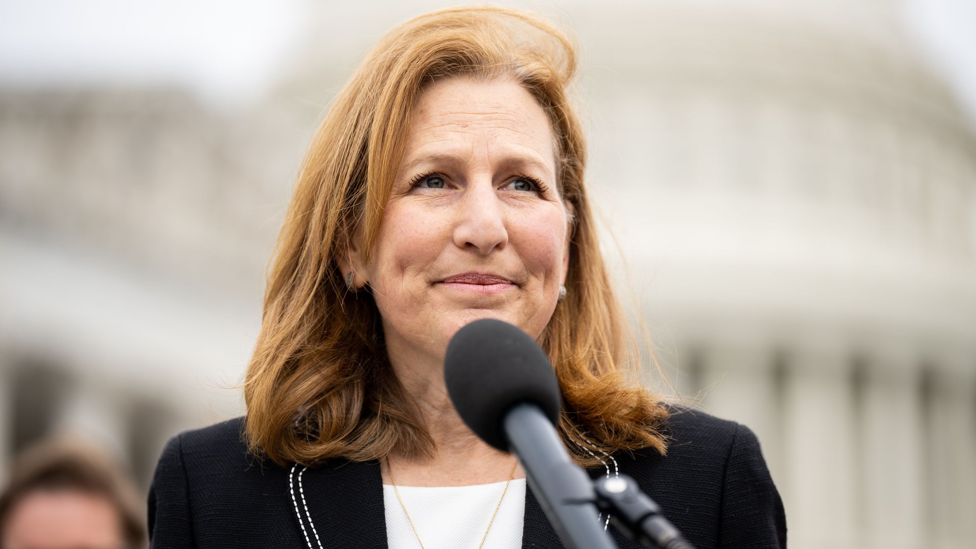 U.S. Rep. Kim Schrier, stands at a microphone in front of the U.S. Capitol.
