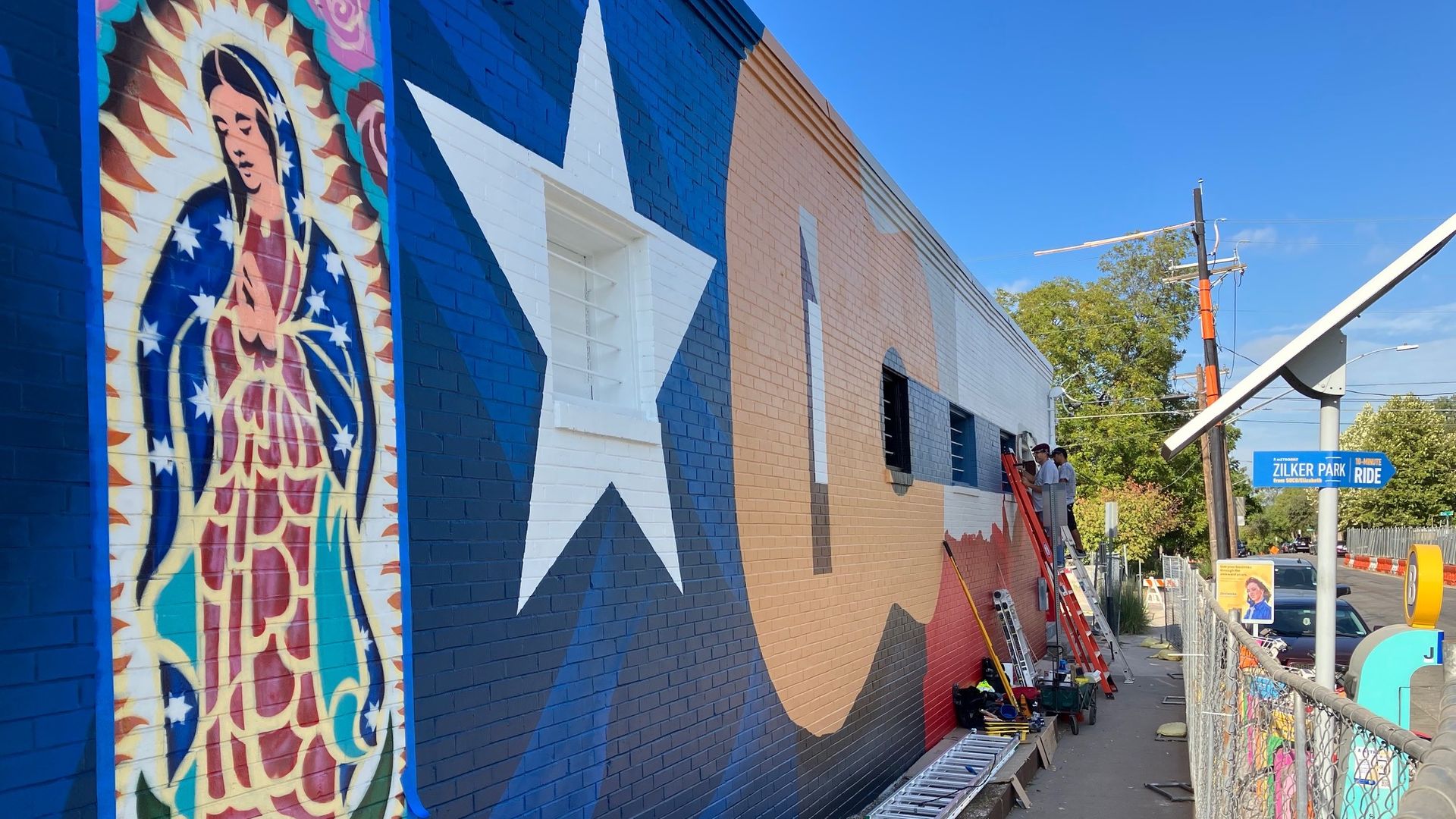 Muralists finishing their work on a South Austin street