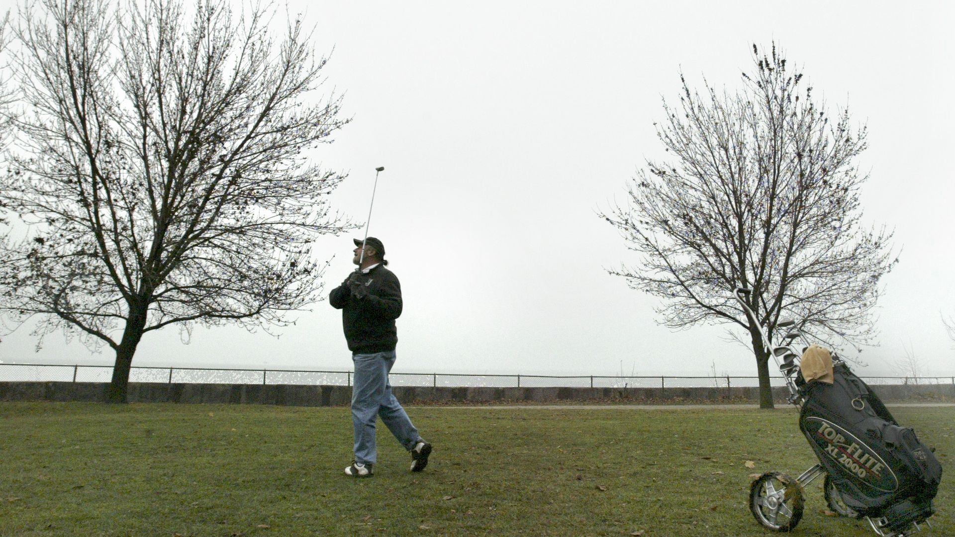 A photo of a man golfing in cold weather.
