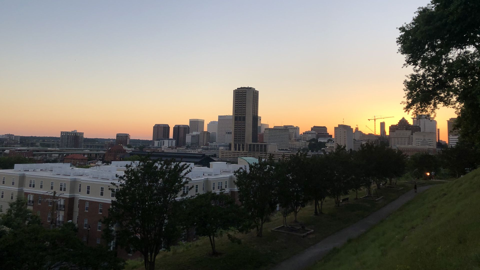 A sunset overlooking the Richmond skyline from a park with green grass and trees