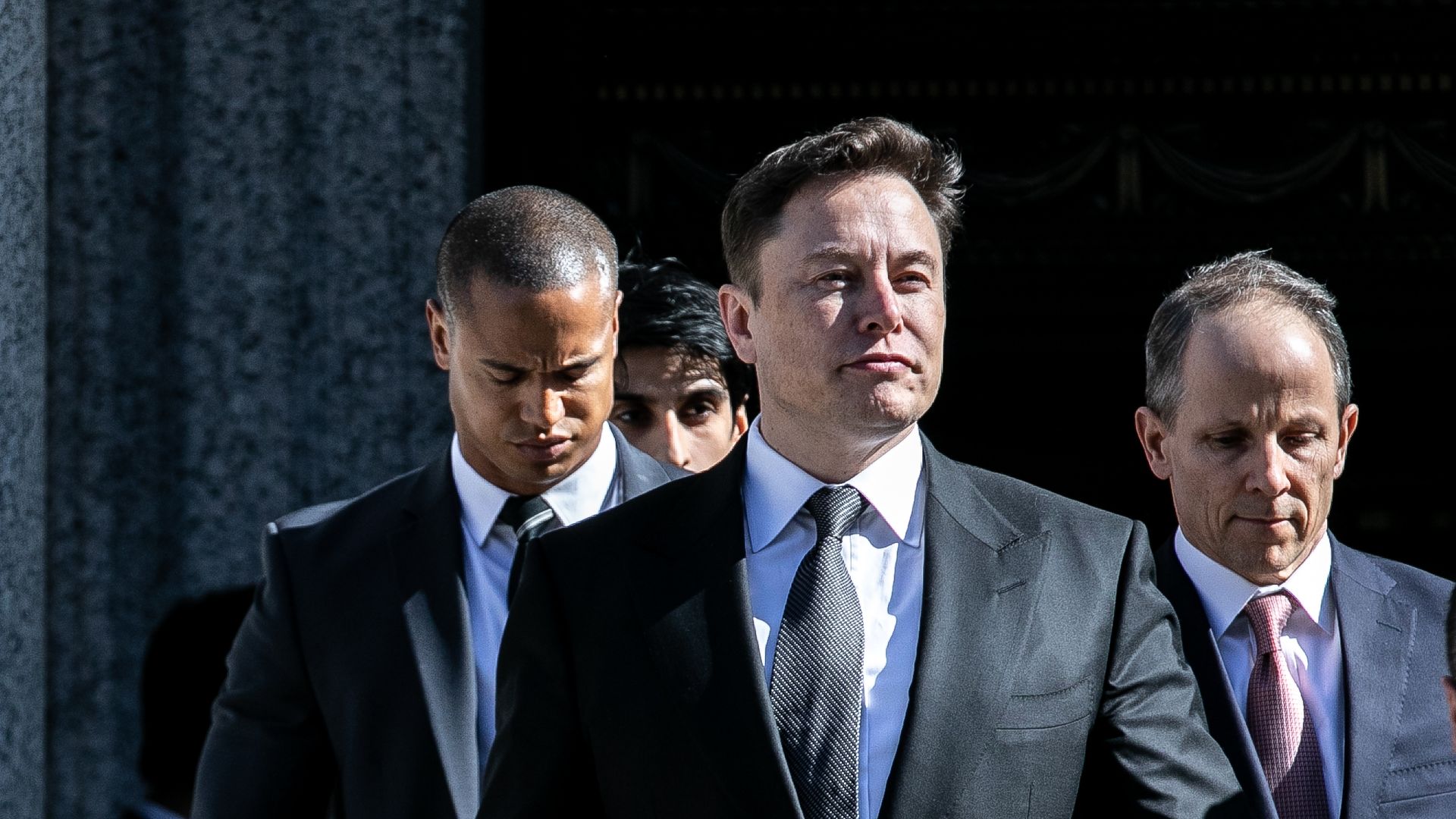 Photo of Elon Musk walking with bodyguards behind him