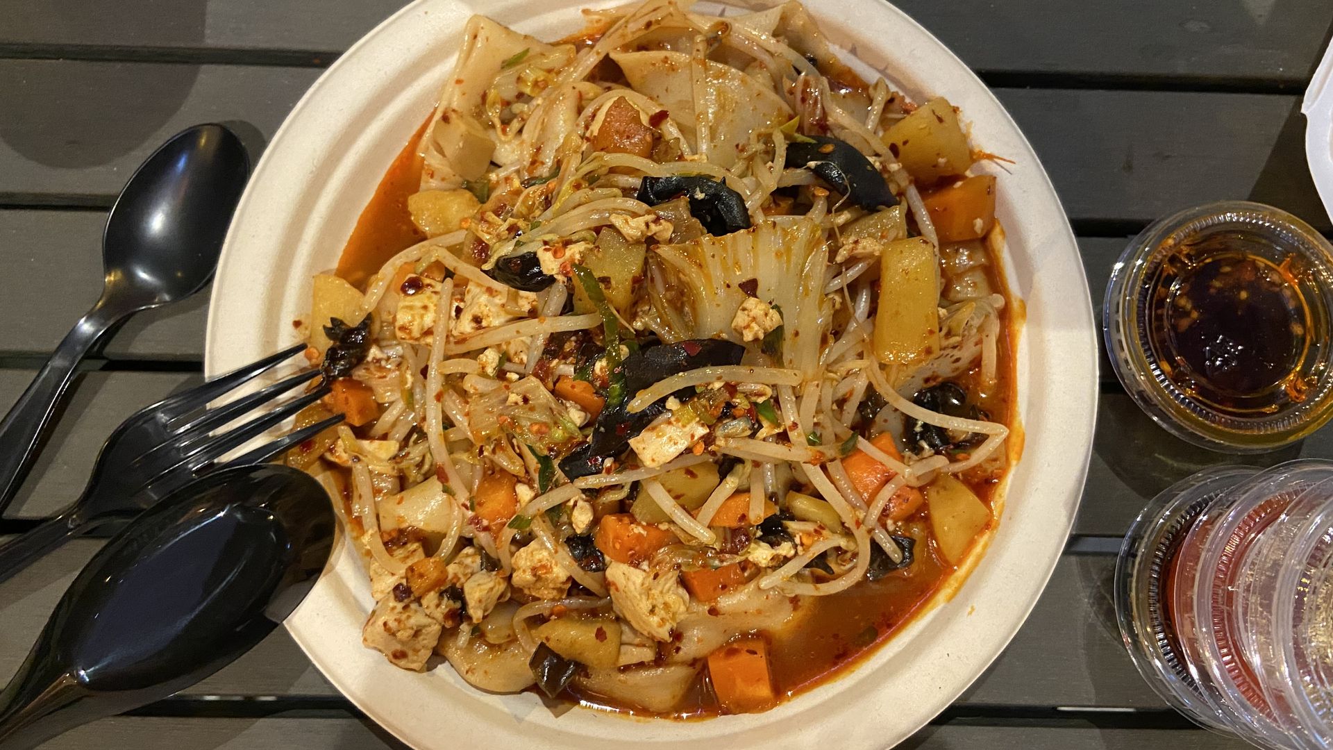 An overhead shot of spicy Chinese noodles with tofu, carrots and mushrooms