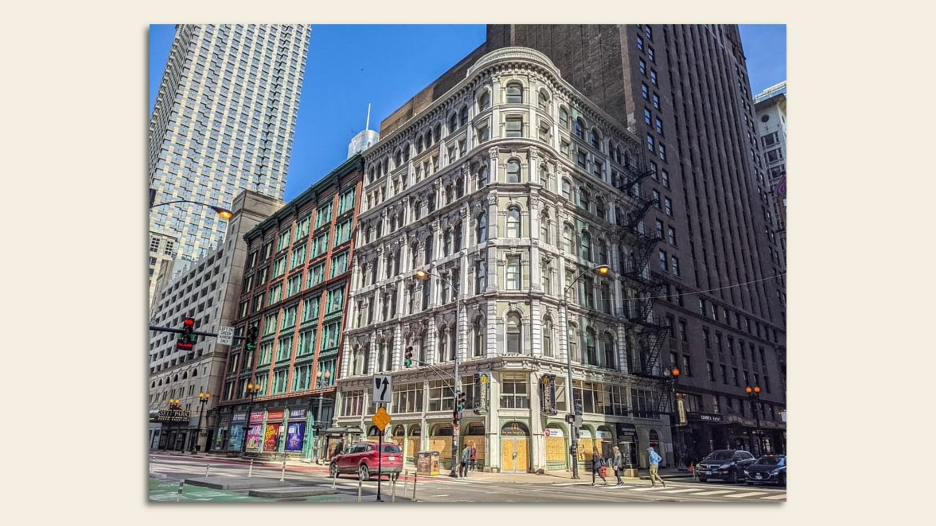 An Italianate building in front of skyscrapers and on a city street.