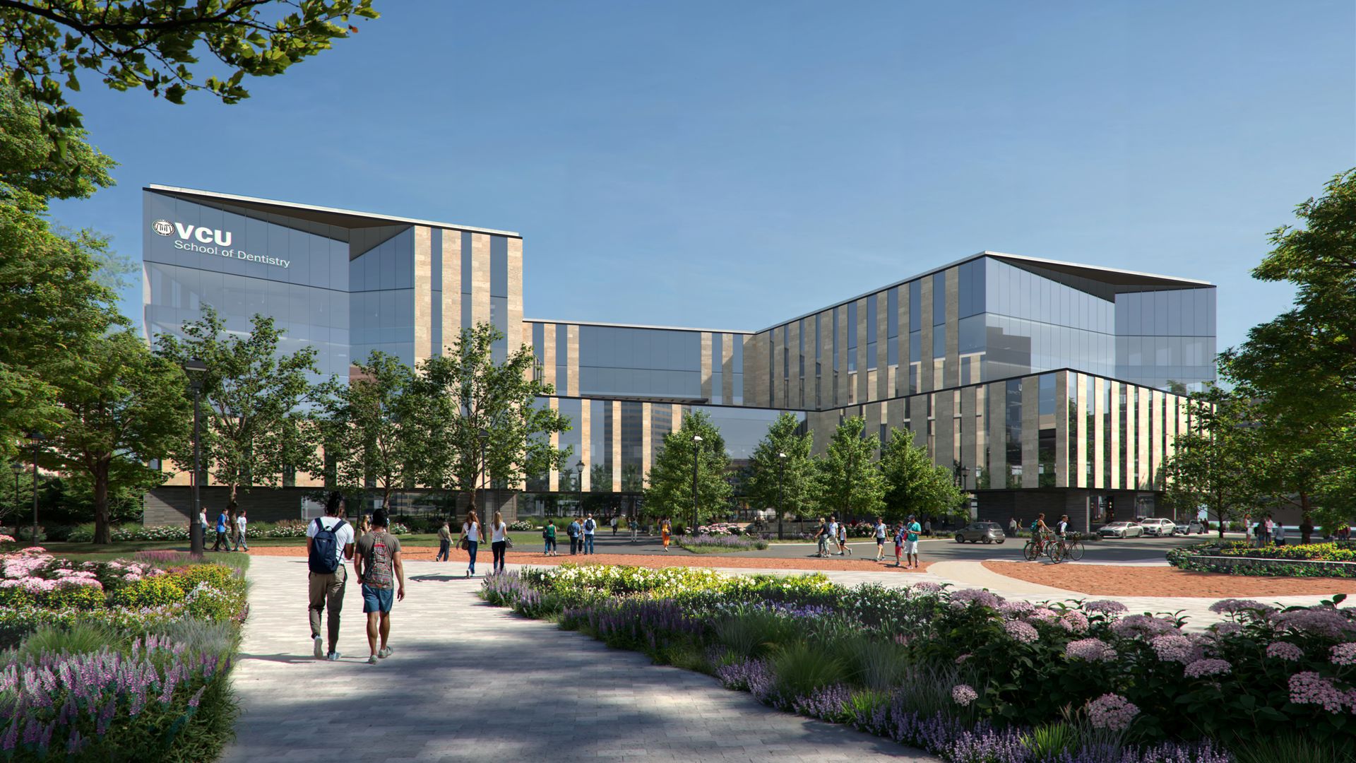 Sunny campus scene with a modern glass building on the left labeled "VCU School of Dentistry," lush landscaping, trees, and people walking along a wide path under a clear blue sky.