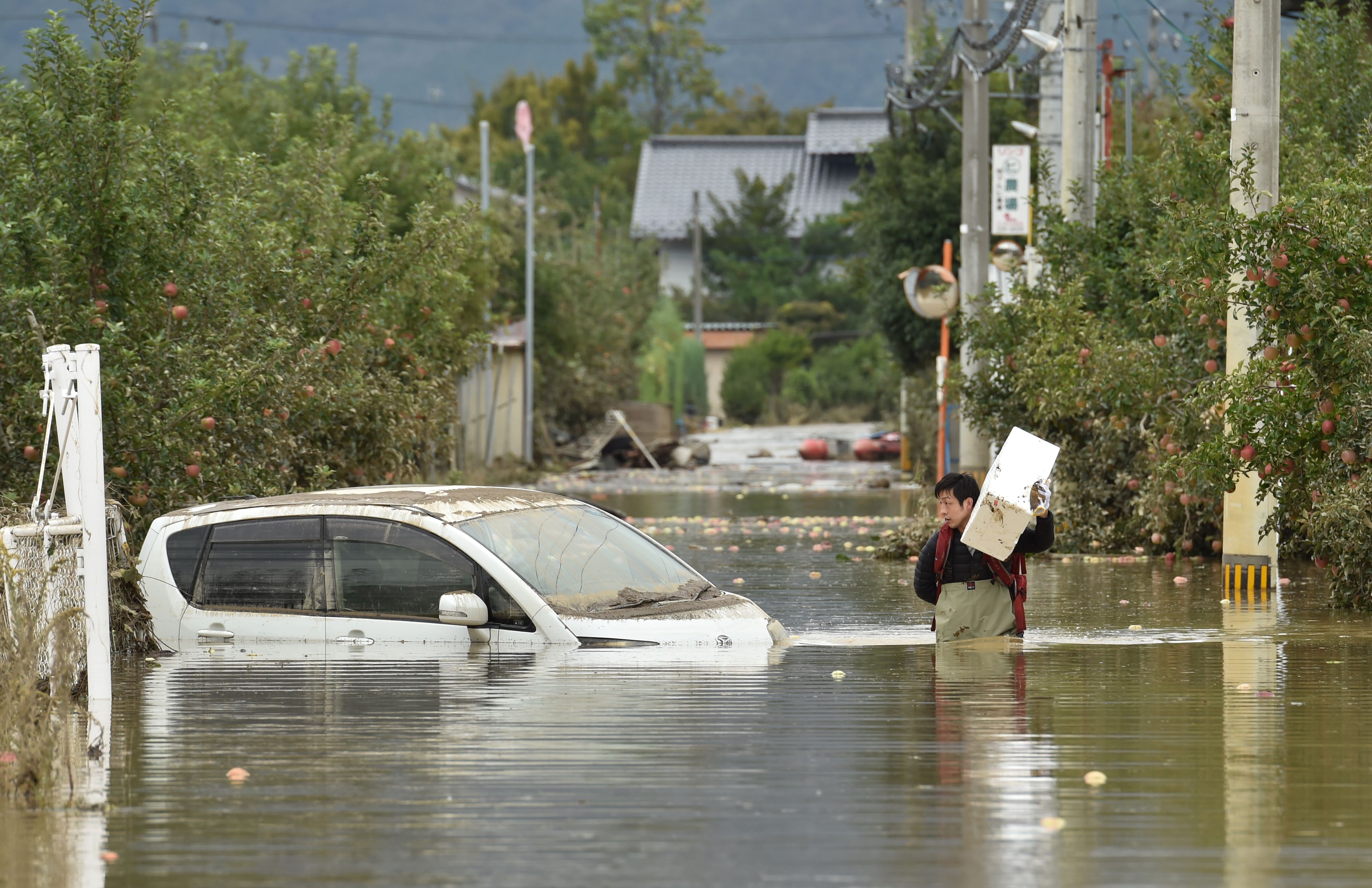  A man wades through floodwaters with items salvaged from his home in the aftermath of Typhoon Hagibis in Nagano on October 14