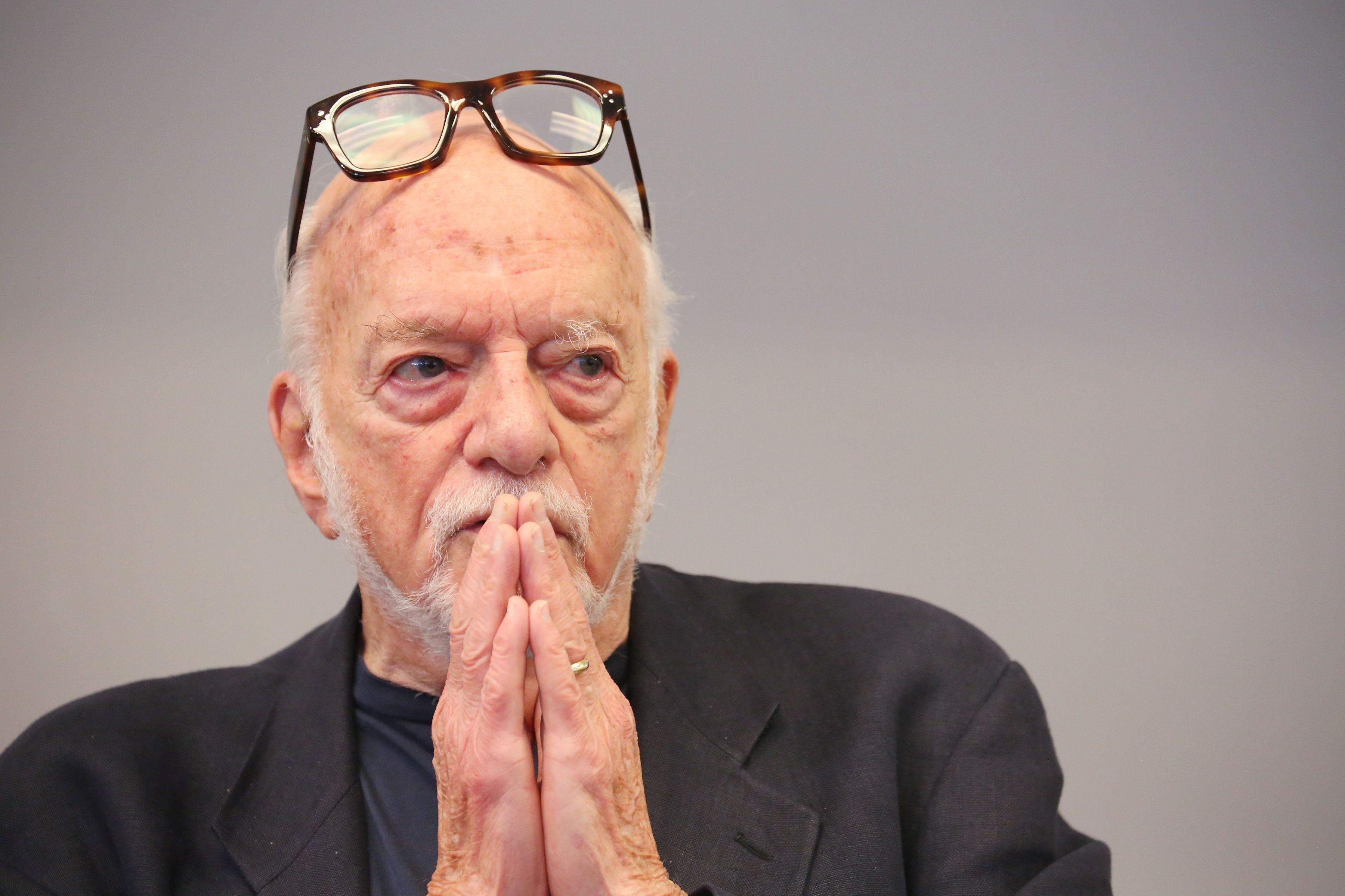 In this image, Hal Prince sits with glasses on his forehead.