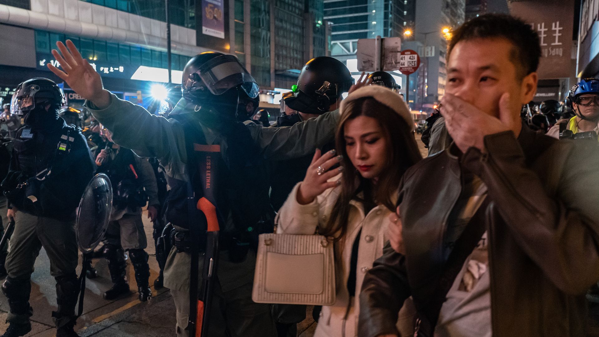 Riot police motion pedestrians away on a street during Christmas night in Mongkok district on December 25, 2019 in Hong Kong, China.