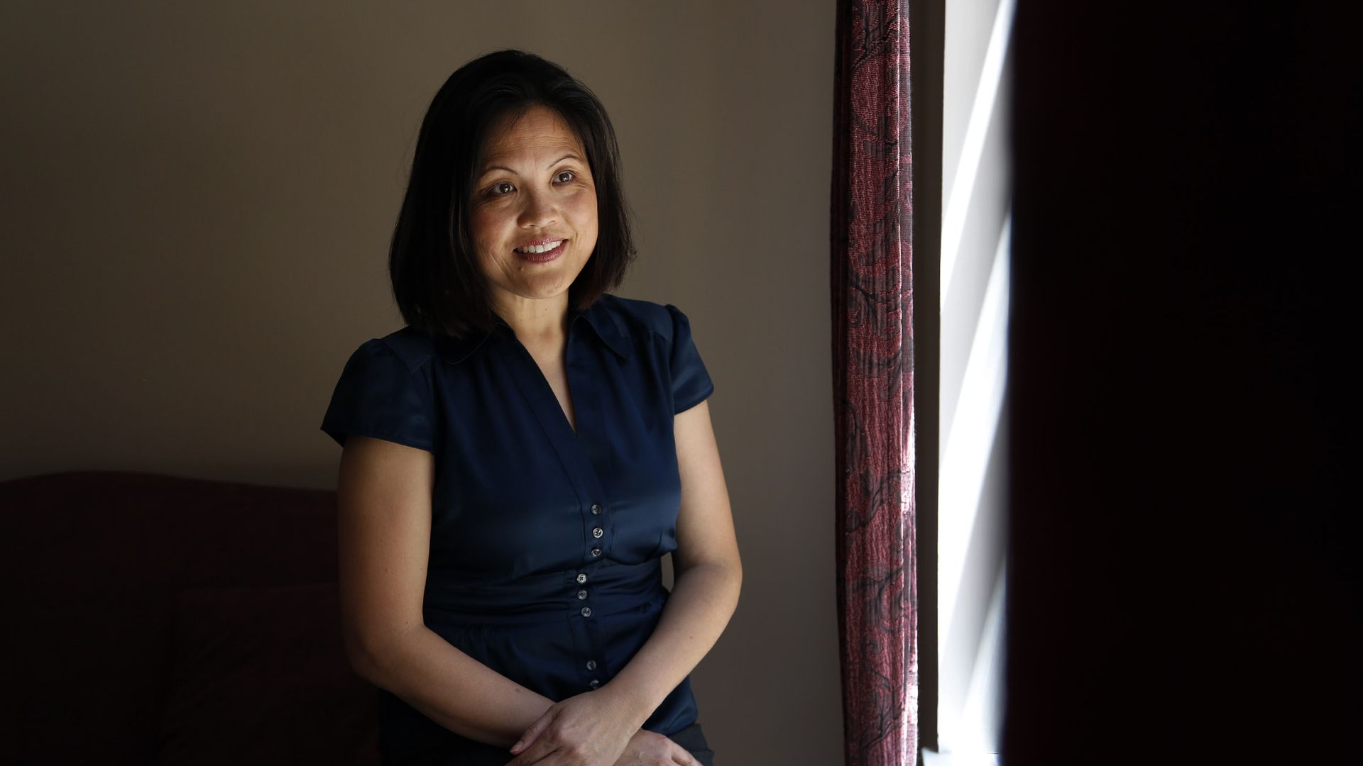 Photo of Julie Su standing for a portrait with her arms crossed in front