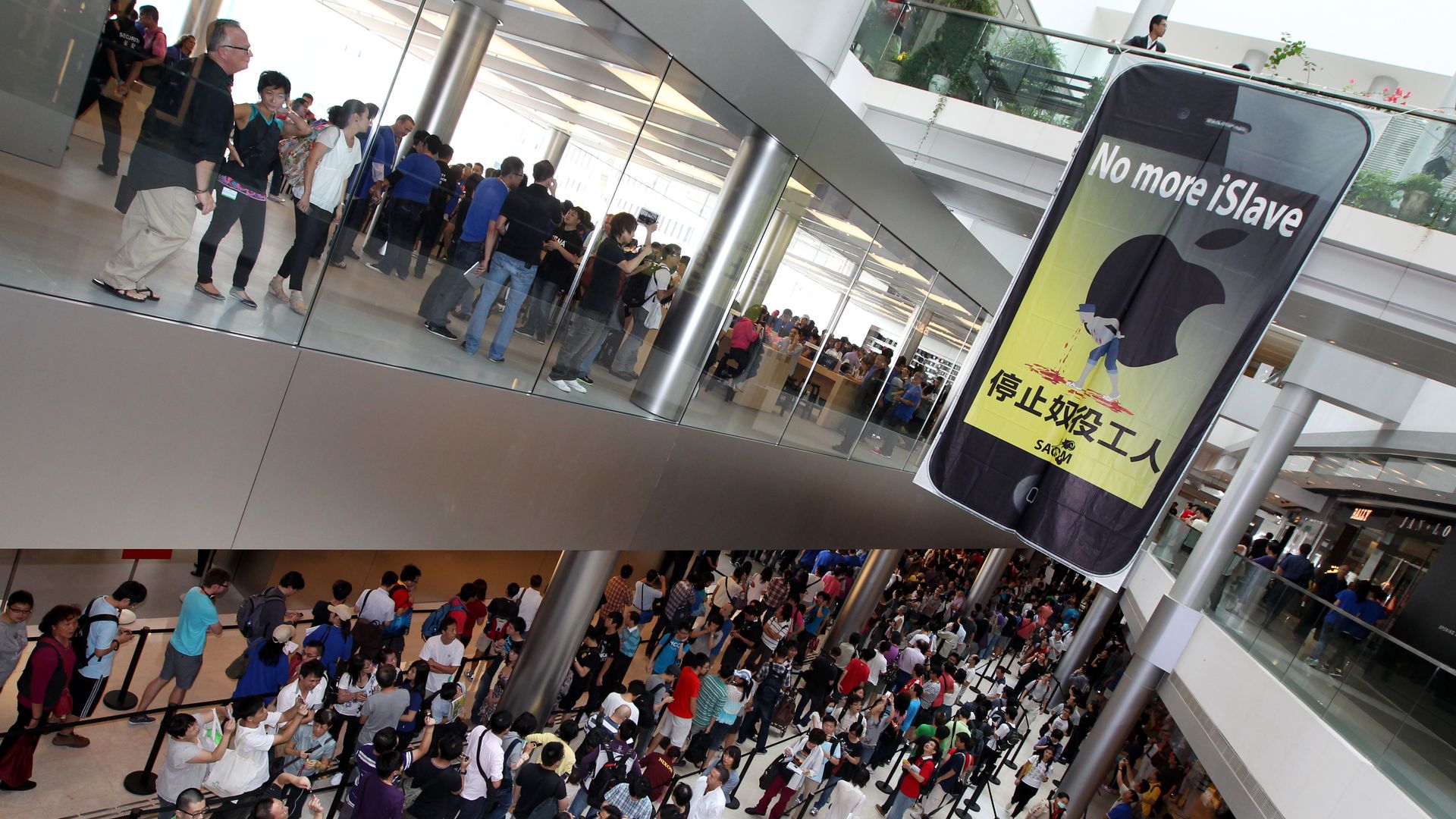 Picture of a mall with long lines and a sign depicting an iPhone screen that reads "no more iSlave."