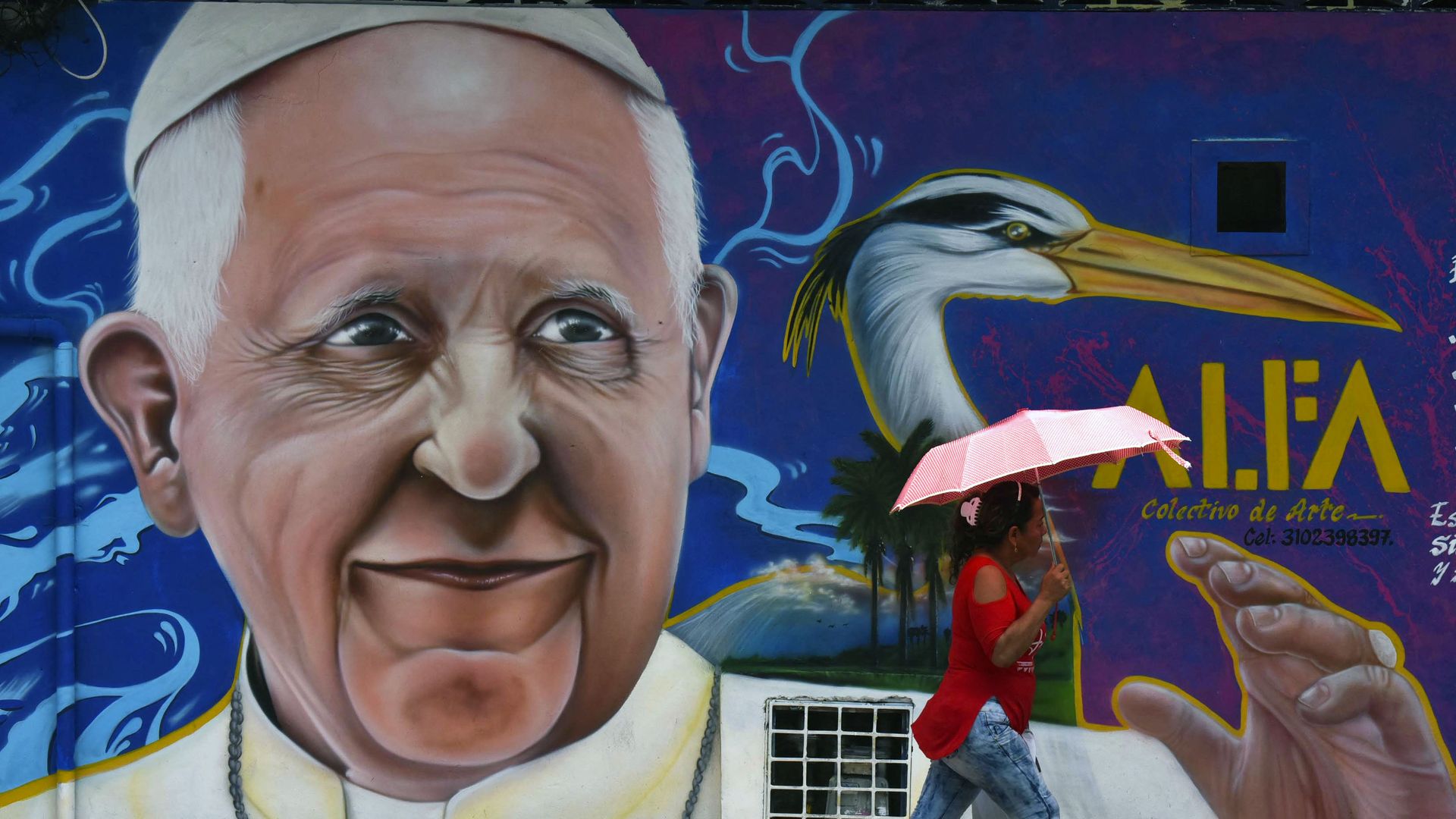 A passer-by walks past a painting of Pope Francis in Villavicencio, Meta, Colombia ahead of his visit in 2017.
