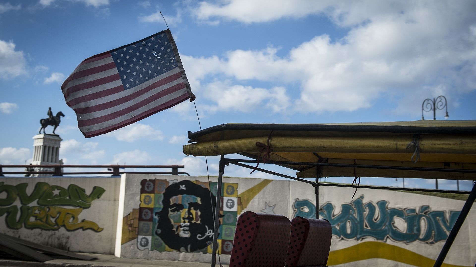A taxi with U.S. flag passes by a wall with the graffiti portrait of Che Guevara in Havana, Cuba, on February 12, 2015.