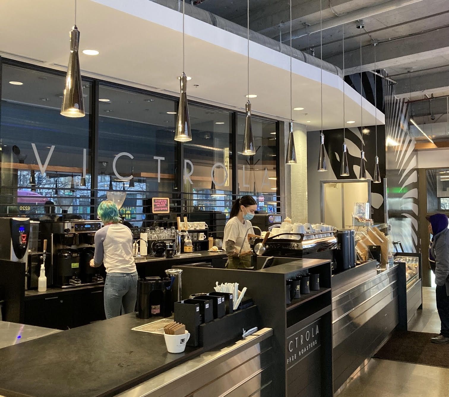 A view of a coffee counter with registers and hanging lamps.